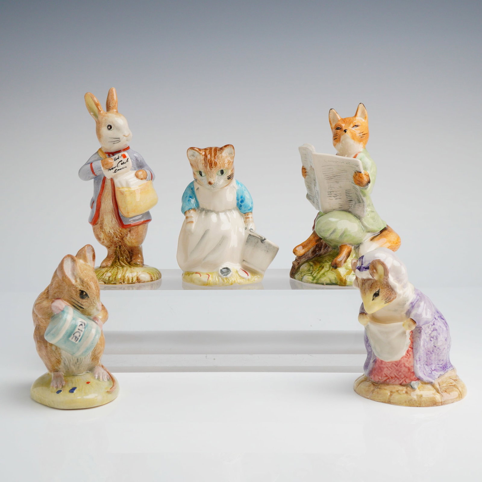 Collection of Five Royal Albert Beatrix Potter Figurines: A collection of five hand-painted glazed ceramic figurines attributed to the Royal Albert Beatrix Potter series. The group features anthropomorphic animal characters standing on small, molded naturali