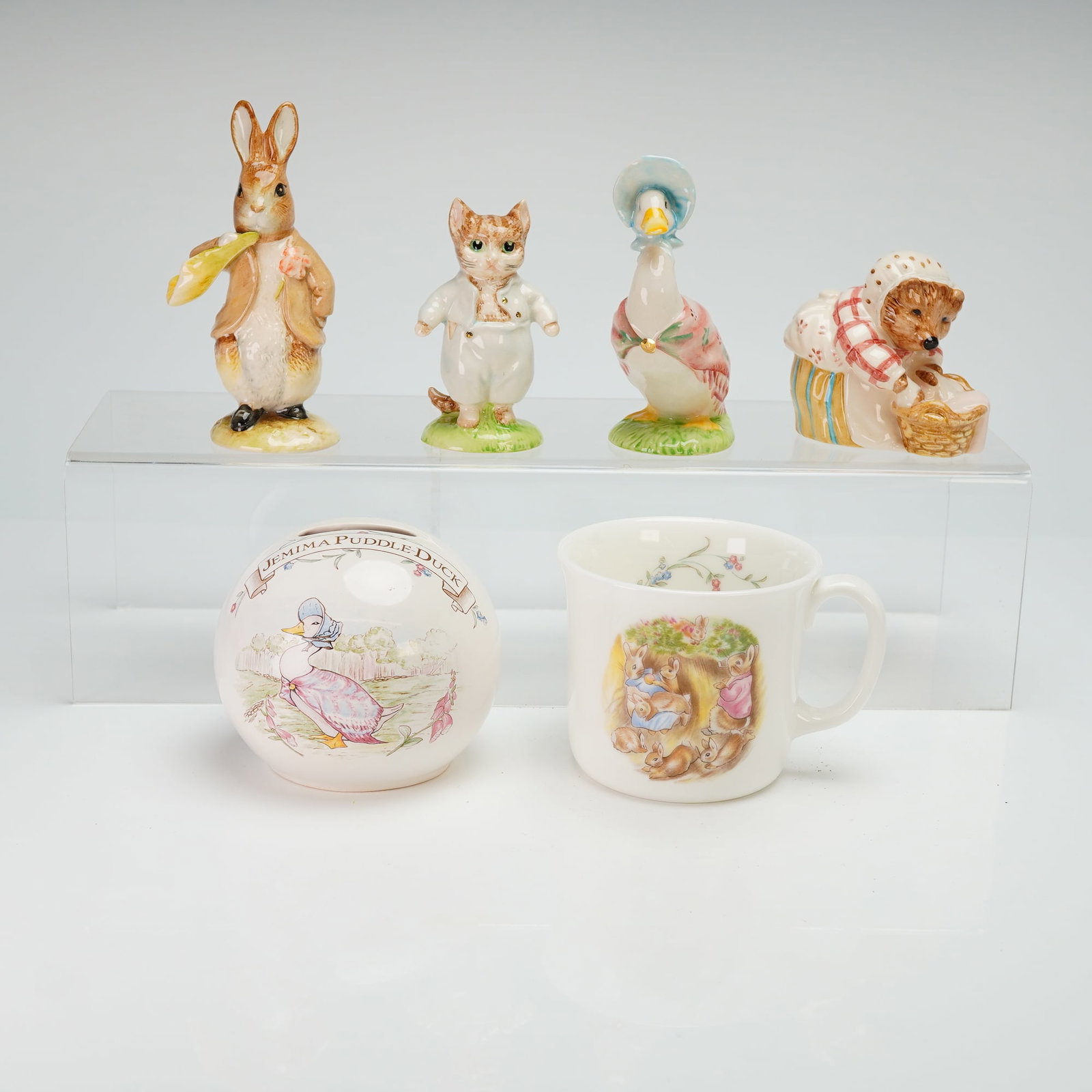 6pc Beswick Ware Beatrix Potter Figurines and Royal Albert Mug & Coin Bank: The figurines include the characters Tom Kitten, Benjamin Bunny (marked Benjamin ate a lettuce leaf), Jemima Puddle-Duck, and Mrs. Tiggy-Winkle. The additional pieces consist of a Royal Albert spheric