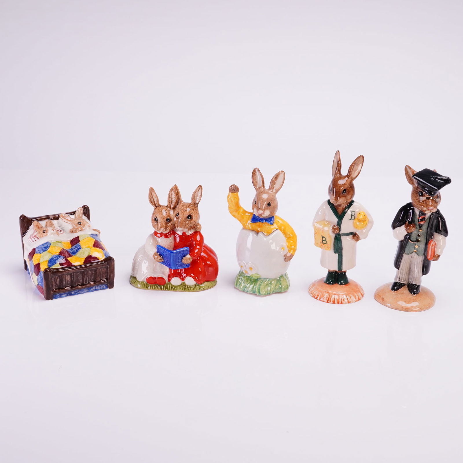 Collection of Five Royal Doulton Bunnykins Figurines: A collection of five polychrome glazed porcelain anthropomorphic figurines from the Royal Doulton Bunnykins series. The collection includes various scenes and professions. Specific figures include: a