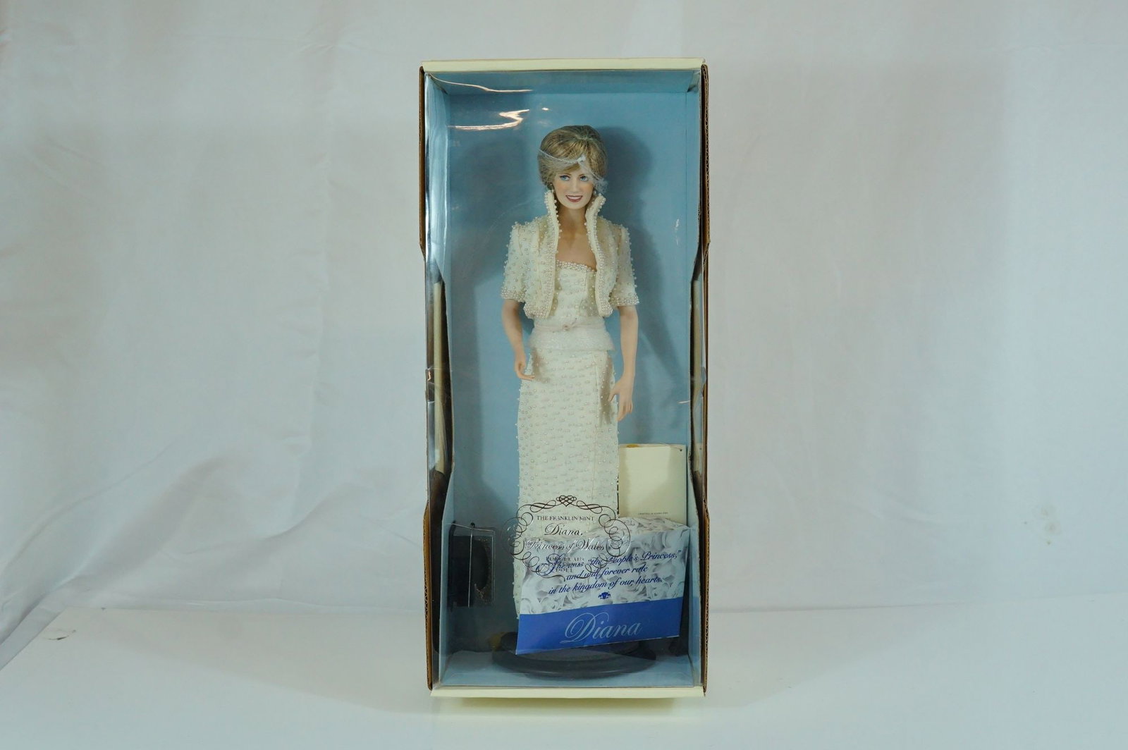 The Franklin Mint Diana, Princess of Wales Porcelain Portrait Doll, 17.5": Produced by The Franklin Mint, this porcelain portrait doll depicts Diana, Princess of Wales. The doll is crafted from fine bisque porcelain with hand-painted facial features, fixed blue eyes, and scu