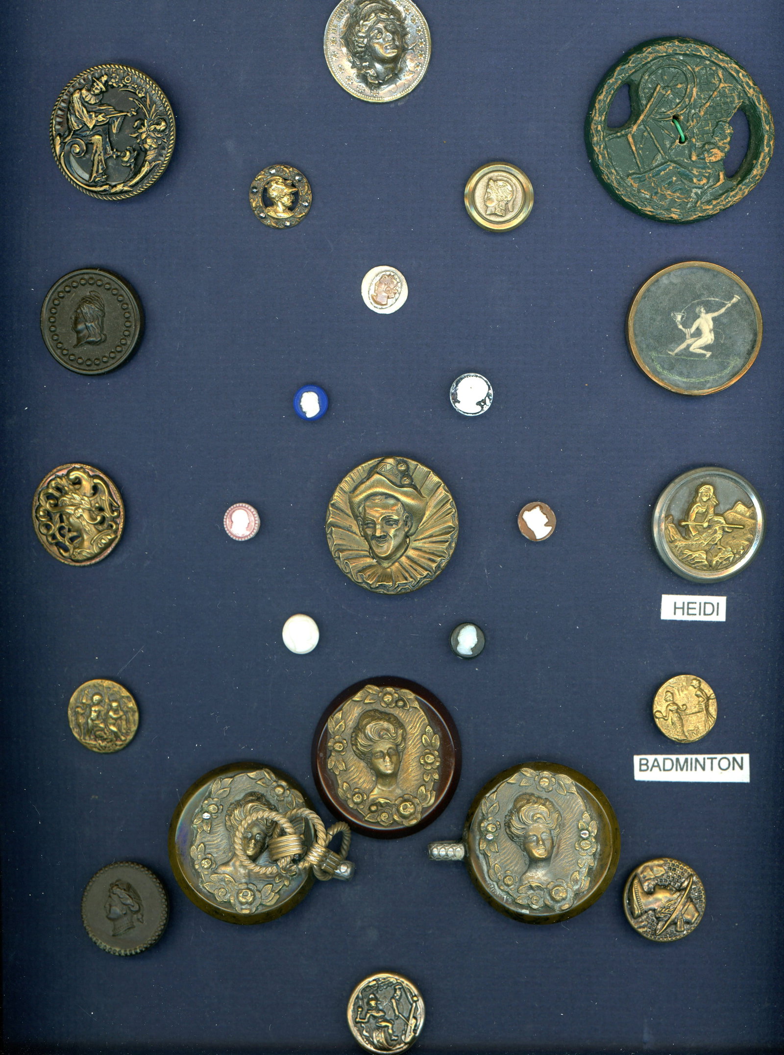 A CARD OF DIVISION 1 & 3 HEADS AND FIGURAL BUTTONS: 23 S/M/L 19th/20th C. examples plus a matching Buckle. This card includes a brass escutcheoned Bakelite button with the matching Buckle. The card also includes glass, brass, Burwood lady at the spinni