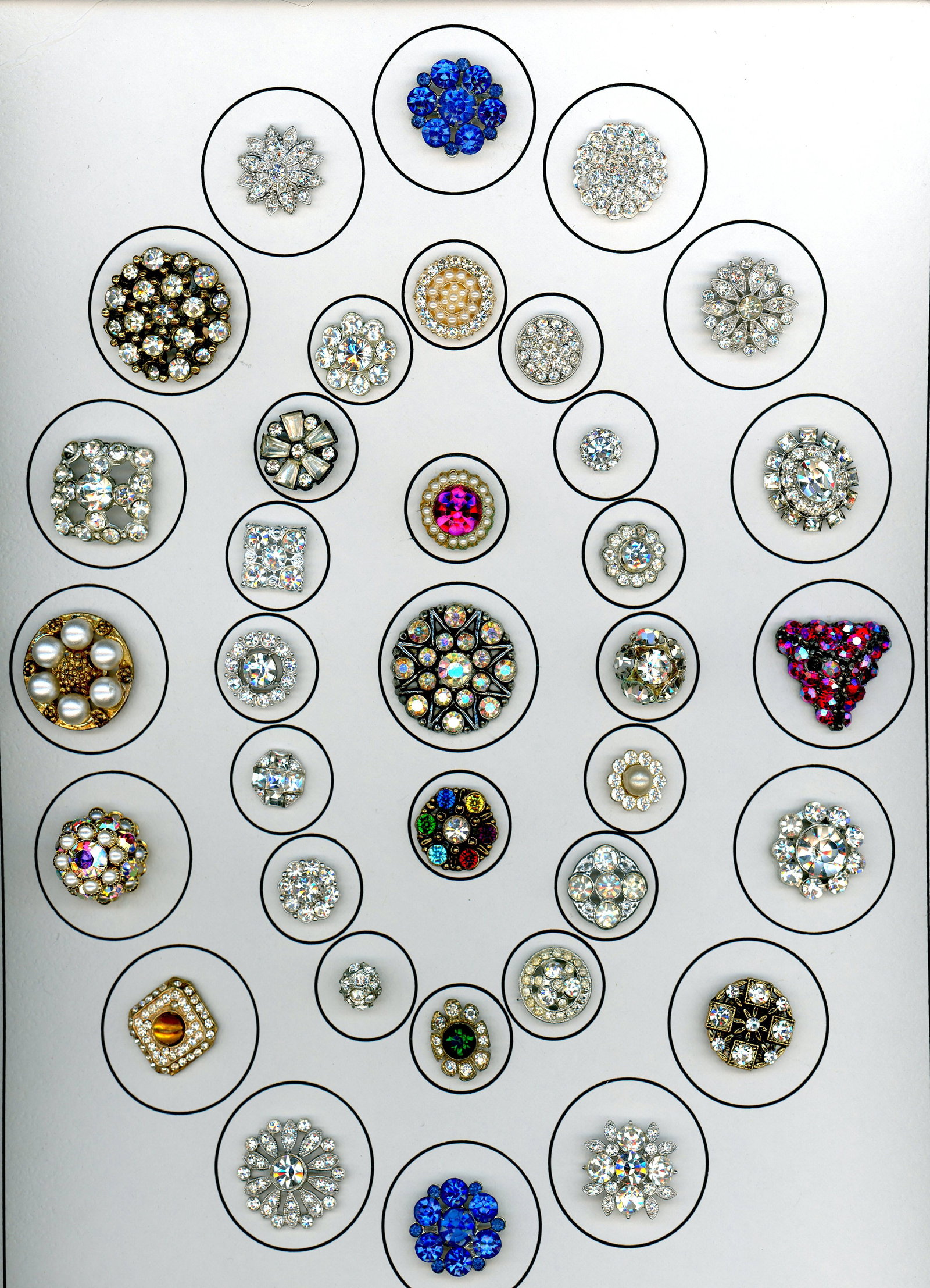 A CARD OF DIVISION THREE "GLITZ" BUTTONS: 5 S/M 1930's to 1950's paste jewel examples. This card includes a variety of shapes. A few colors and a nice selection of clear pastes. DimensionsSM=Less than 3/4", Medium=3/4" to 1 1/4". Large=1 1/4"