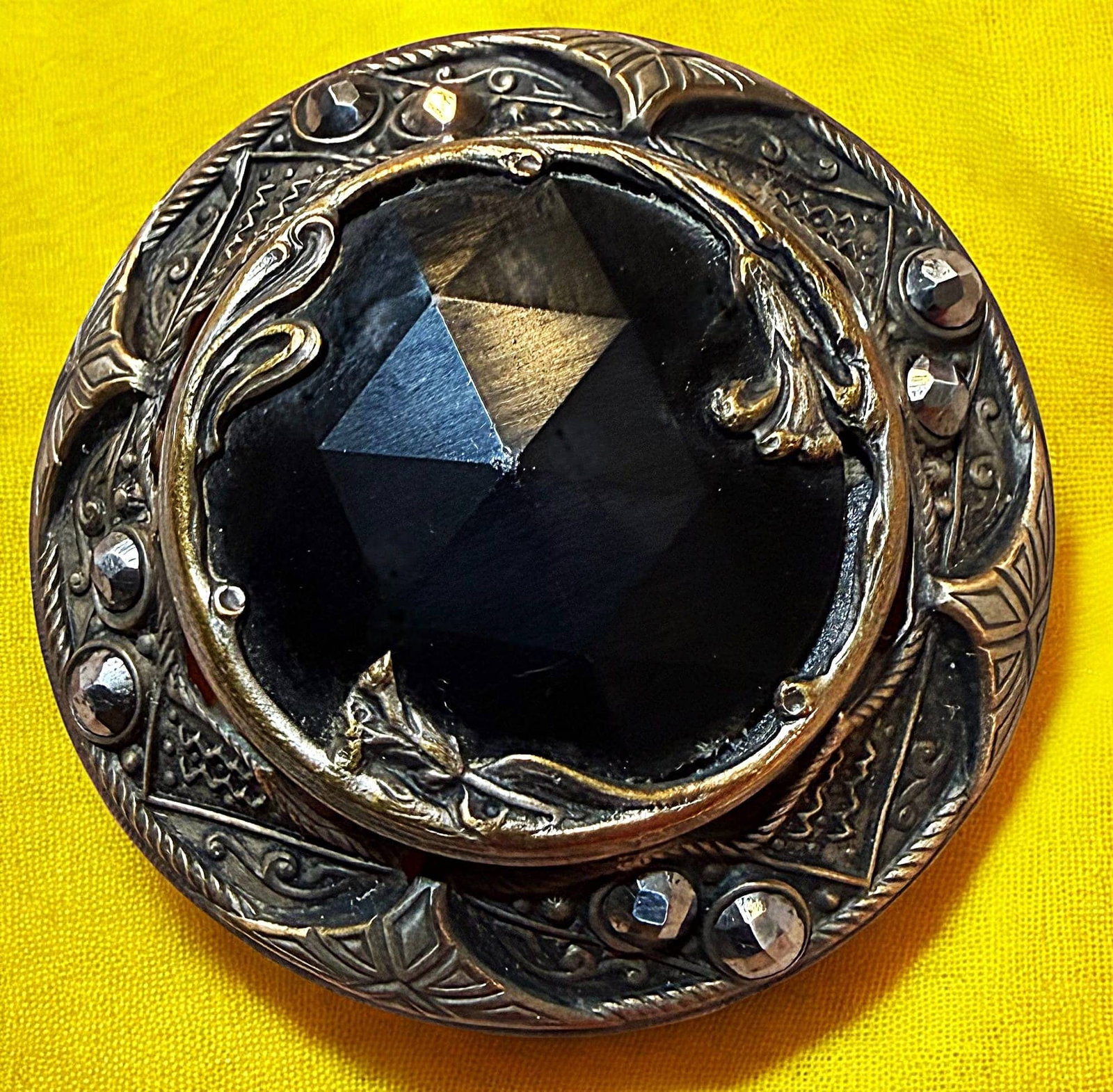 A DIVISION ONE VICTORIAN JEWELED BUTTON: 1 Large 19th century pierced brass GAY 90 example. Here is a lovely example of genuine Gay 90 jeweled button from the 1890's. The pierced ornate brass example is centered with a large faceted black gl