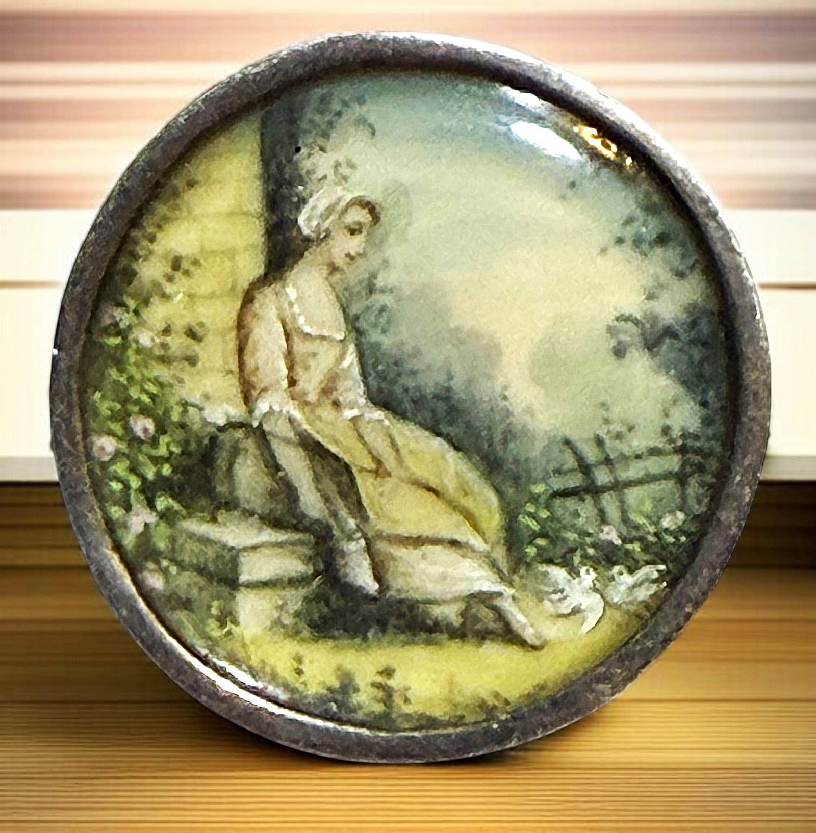 A DIVISION ONE HAND PAINTING UNDER GLASS BUTTON: 1 Medium 19th century female figural example. This is a beautifully hand painted in pastel colors on natural material and set under glass and mounted in a high quality silver setting. The women is see
