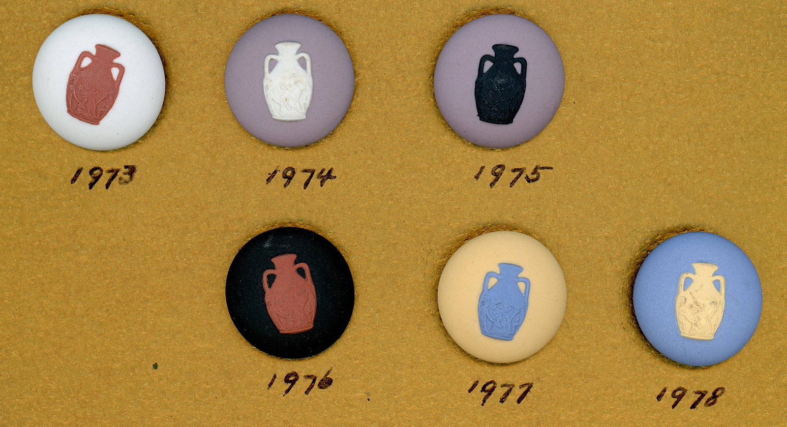 A SELECTION OF DIVISION THREE WEDGWOOD BUTTONS: 6 Medium 20th century Wedgwood seminar favor buttons. Like the button societies, the Wedgewood society gives a favor button each year of their conventions. Every year a different coloration of the sam