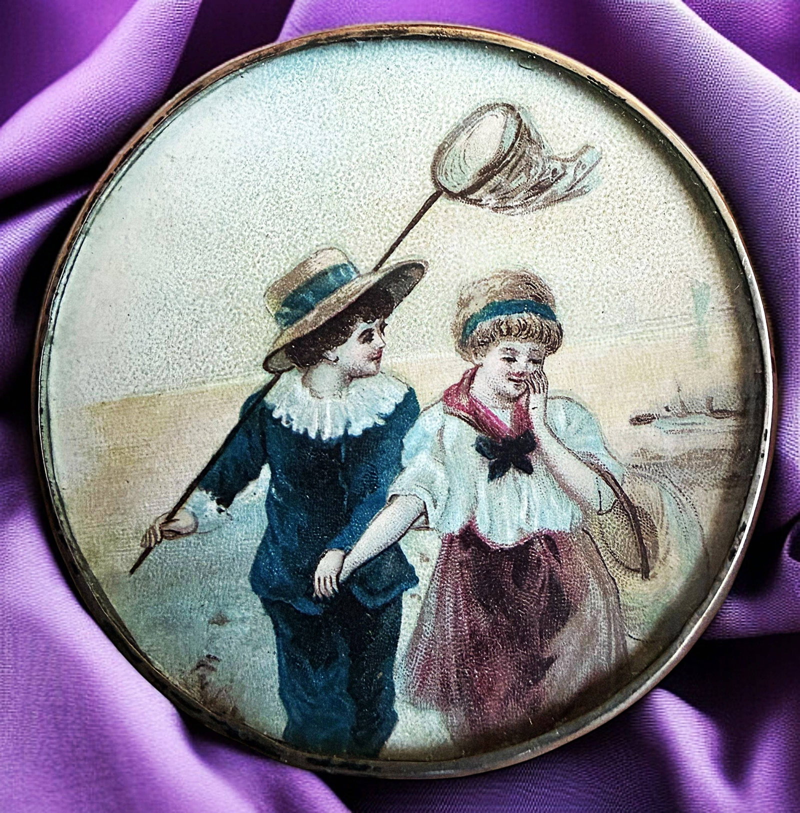A DIVISION ONE PICTORIAL UNDER GLASS BUTTON: 1 Extra Large late 19th early 20th C. hand painting of children. This is actually a transfer on paper under glass with beautiful hand coloring in plum and blue colorations. The depiction is of a boy a