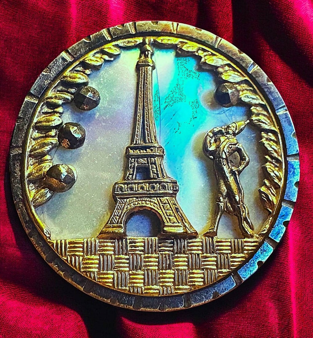 A DIVISION ONE SHELL AND FIGURAL STEEL CUP BUTTON: 1 Medium 19th century Eifel Tower and French Fop example. The pearl on the background of this brass pictorial steel cup button is so colorful and has great chatoyancy. DimensionsSM=Less than 3/4", Med