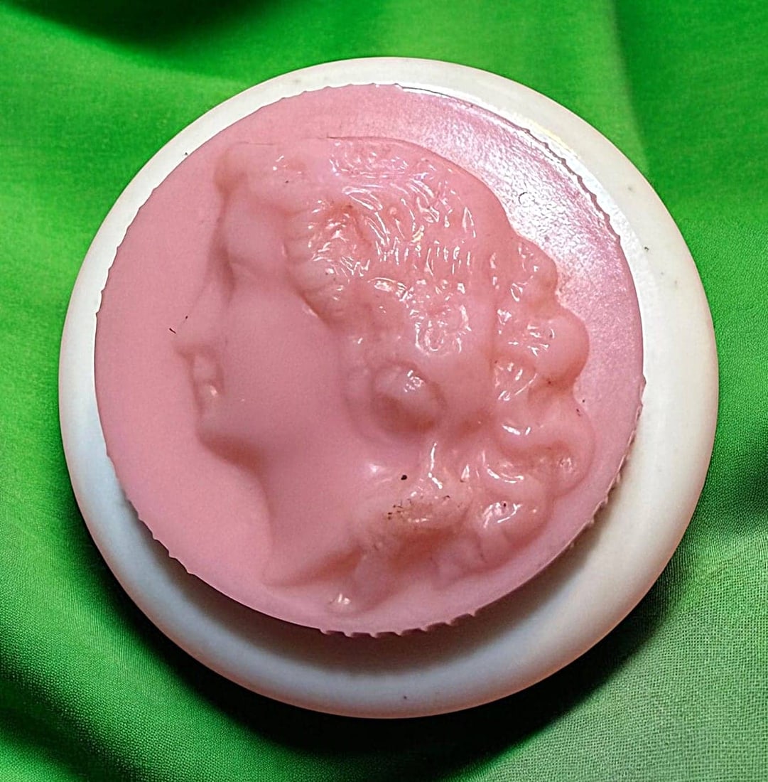 A DIVISON THREE TWO PART COLT BUTTON: 1 Medium 20th C, rouge button from the Colt Manufacturing Co. These Rouge buttons are very desirable among collectors. This example has a pink screw on cap with the typical molded ladies head on a