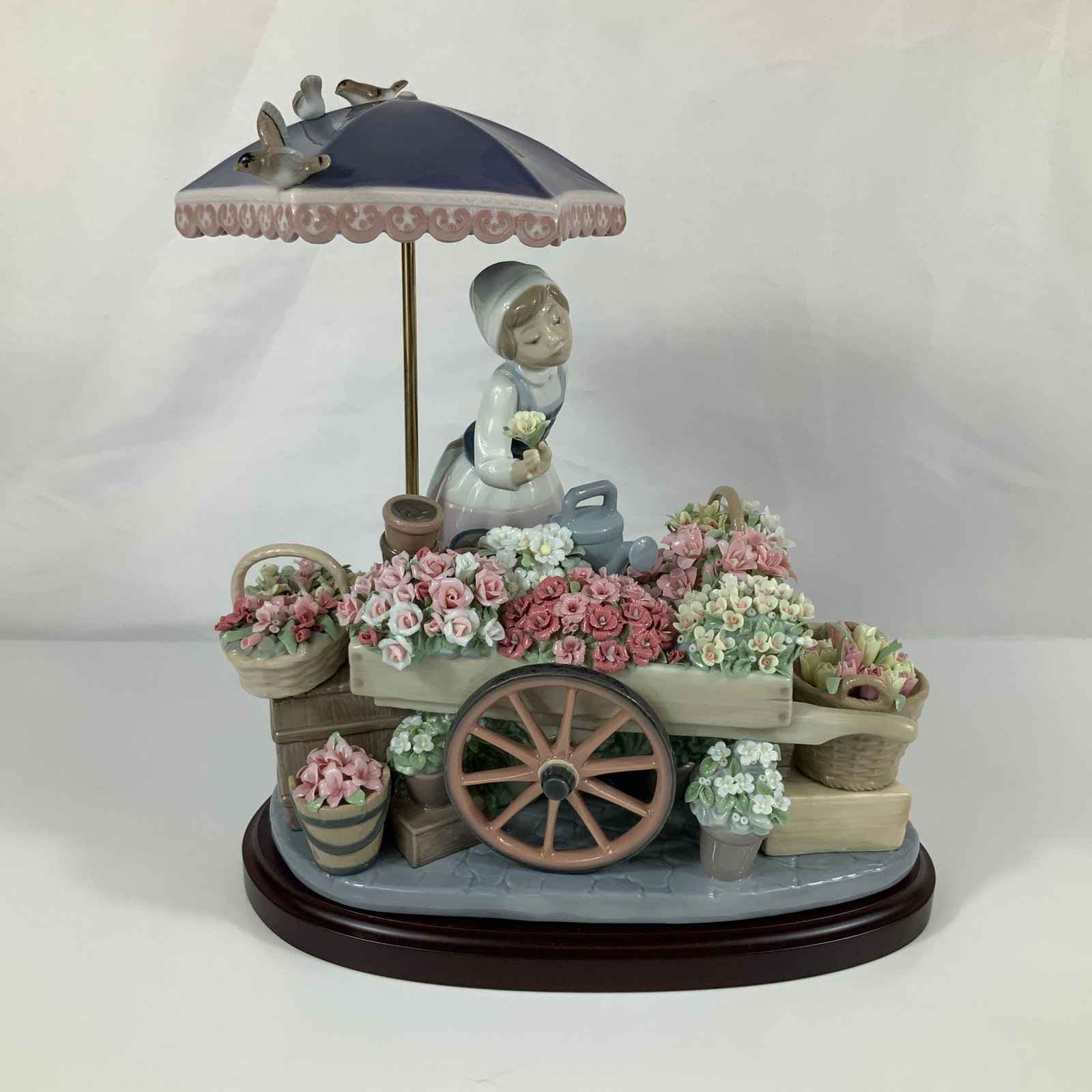 Lladro Flowers of the Season Porcelain Figurine Model 1454: This Lladro porcelain figurine, titled Flowers of the Season (Vendedora de Flores), is model number 1454. The complex scene depicts a young woman flower vendor in traditional attire, including an apro