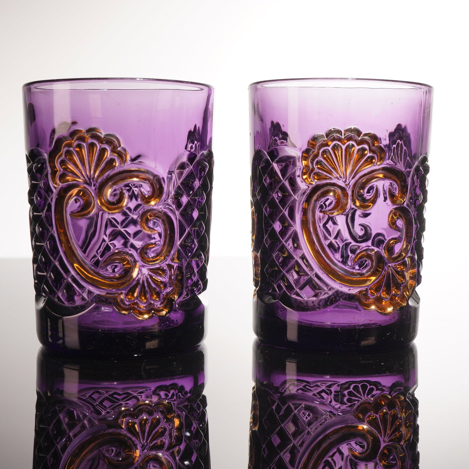 Riverside Glass Works, Croesus Pattern, Pair of Amethyst Glass Tumblers: A pair of cylindrical tumblers in the Croesus pattern (No. 484), produced by the Riverside Glass Works of Wellsburg, West Virginia, circa 1897. These pieces are crafted in deep amethyst glass, often r