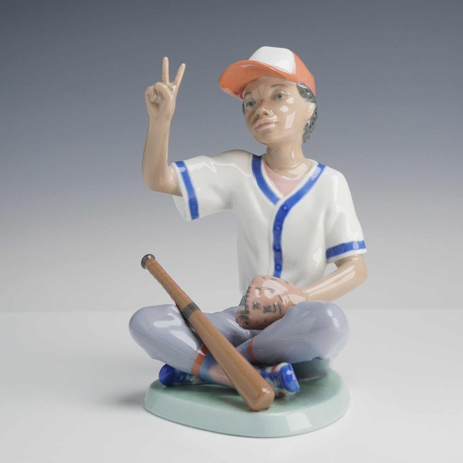 Lladró Baseball Star Figurine #6137, 5.5 Inches: Produced by Lladró in Spain, this glazed porcelain figurine, titled Baseball Star (model #6137), depicts a young boy athlete. The underside bears the blue underglaze Lladró trademark stamp, HAND MAD