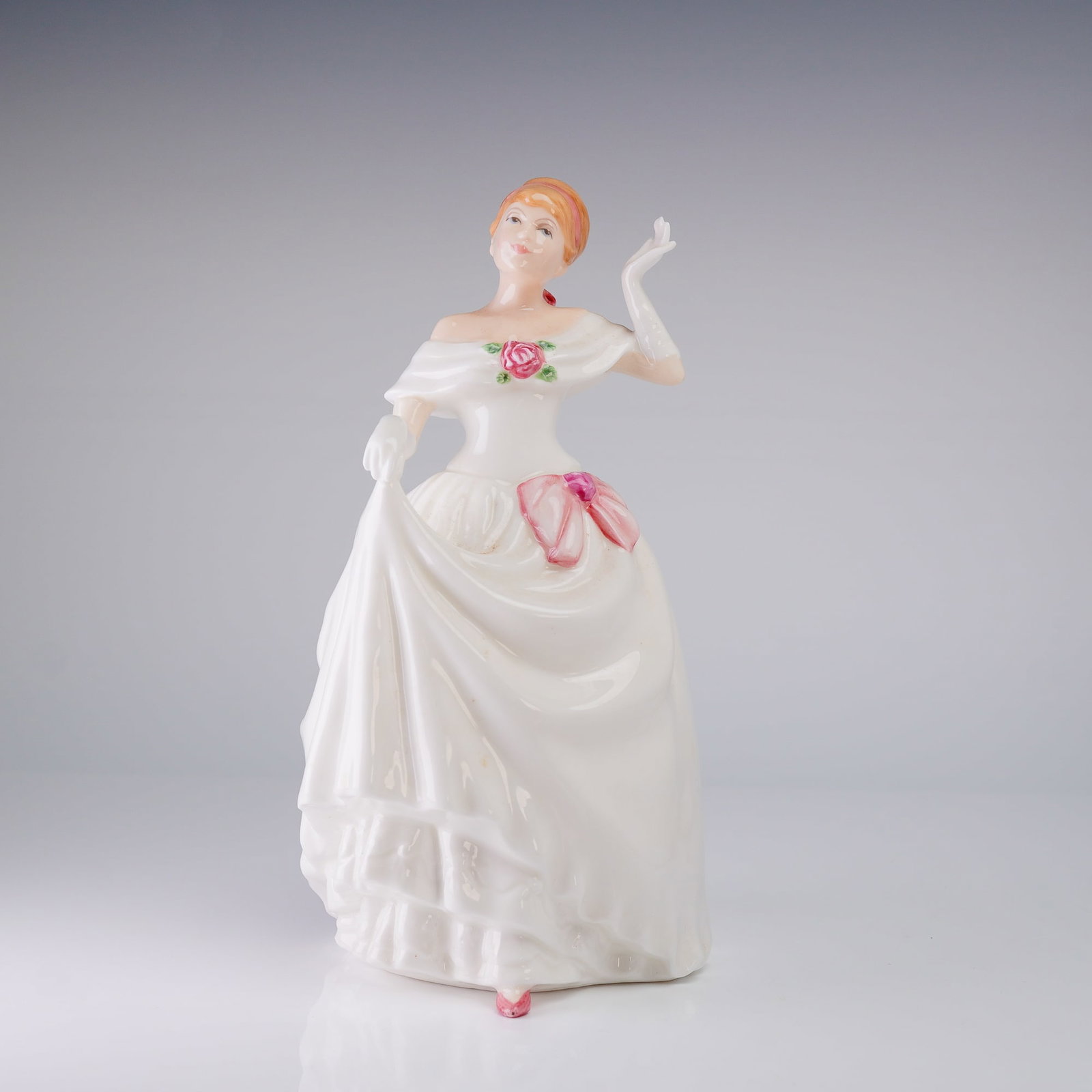 Royal Doulton Figurine Dawn HN3600: A hand-decorated bone china figurine by Royal Doulton, titled Dawn, model number HN 3600. The figure is depicted wearing a flowing, long white evening gown with ruffles, complemented by white opera gl