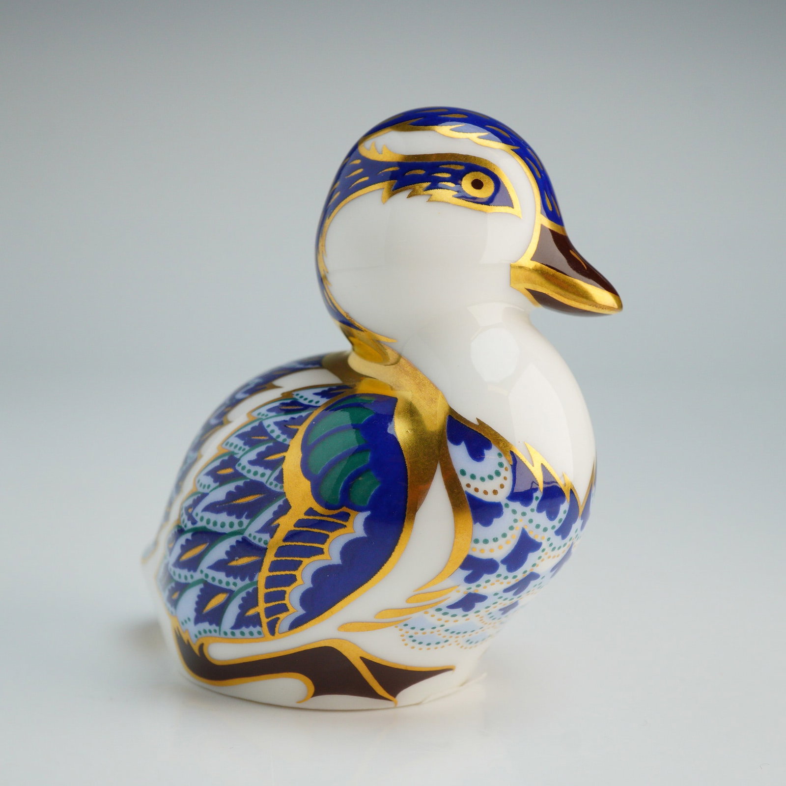 Royal Crown Derby Swimming Duckling Paperweight: Royal Crown Derby fine bone china paperweight modeled as a swimming duckling. The piece is decorated with Imari-style hand-painted patterns in cobalt blue, light blue, green, and russet, with extensiv