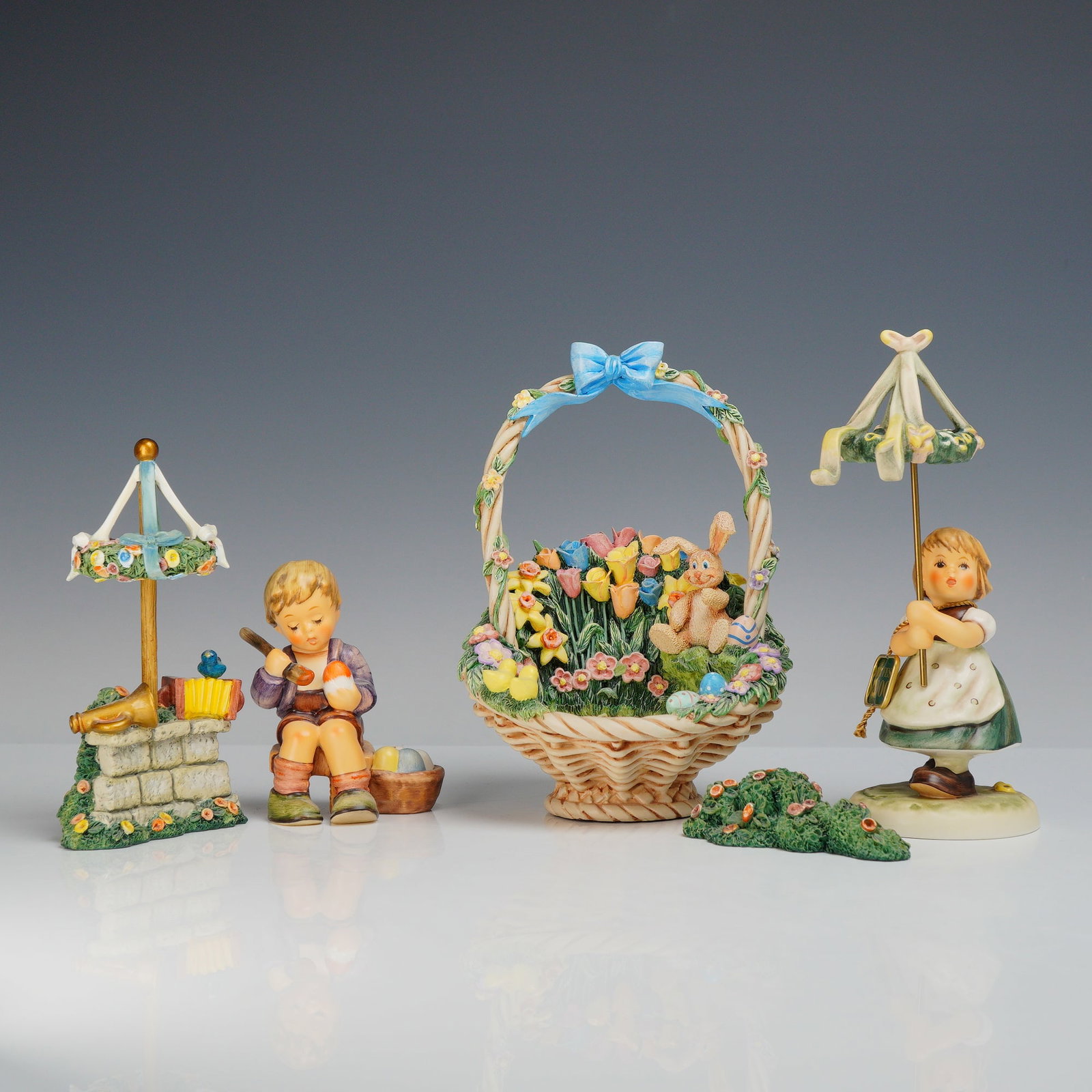 A Set of Goebel Hummel Figurines and Miscellaneous Hummelscape Accessories: This collection includes two Hummel figurines and miscellaneous decorative accessories produced by Goebel. The first figurine, titled Millennium Maifest 2000, depicts a young girl in a green dress and