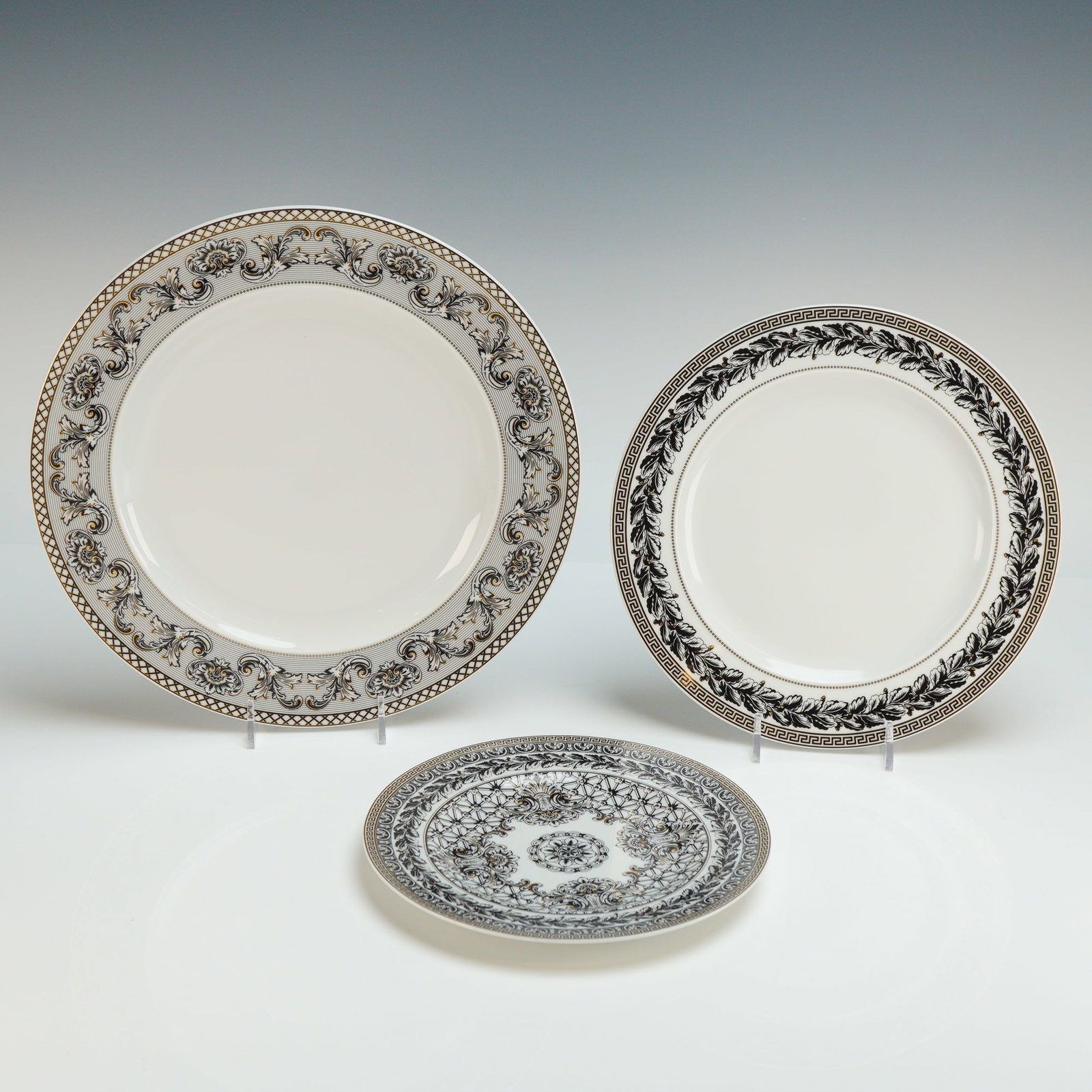 3pc Versace Rosenthal Porcelain Plates, Marqueterie: The porcelain plate set features contemporary design with neoclassical influences. Each piece is decorated with an intricate black, white, and gold-toned motif including acanthus leaf scrolls, Greek k