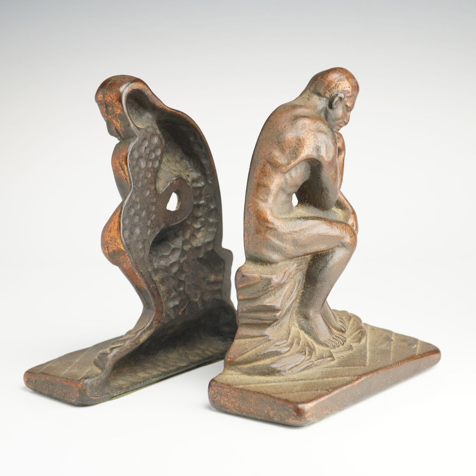 A Pair of Art Deco Cast Metal Bookends Fashioned After Auguste Rodin's The Thinker: A pair of Art Deco cast metal bookends fashioned after Auguste Rodin's The Thinker. Each piece depicts the iconic seated male figure in a contemplative pose, positioned on a rectangular base with a te