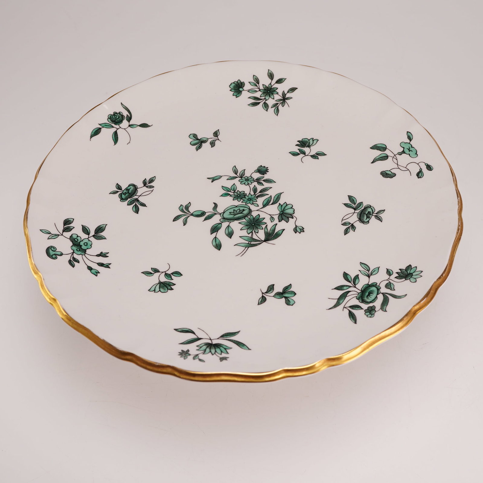 Royal Albert Greensleeves Pattern Bone China Pedestal Cake Stand: A Royal Albert bone china pedestal cake stand or tazza produced in England. The piece features the Greensleeves pattern, which consists of various floral sprays and sprigs depicted in shades of green