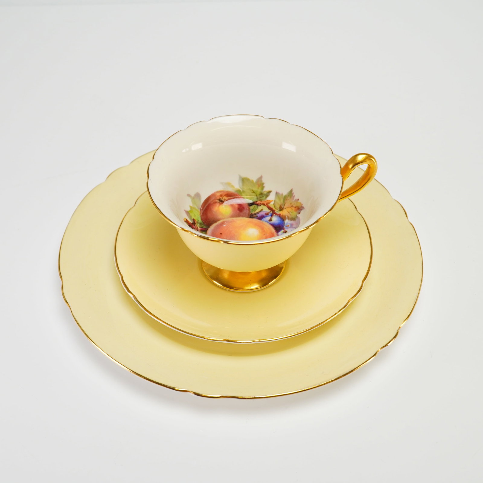 Shelley Fine Bone China Orchard Fruit Pattern Tea Trio in Primrose Yellow: This vintage Shelley fine bone china tea trio set of 3 (2 dishes and 1 cup) with yellow and gold accents was manufactured in England. The set comprises a pedestal teacup, a matching saucer, and a side