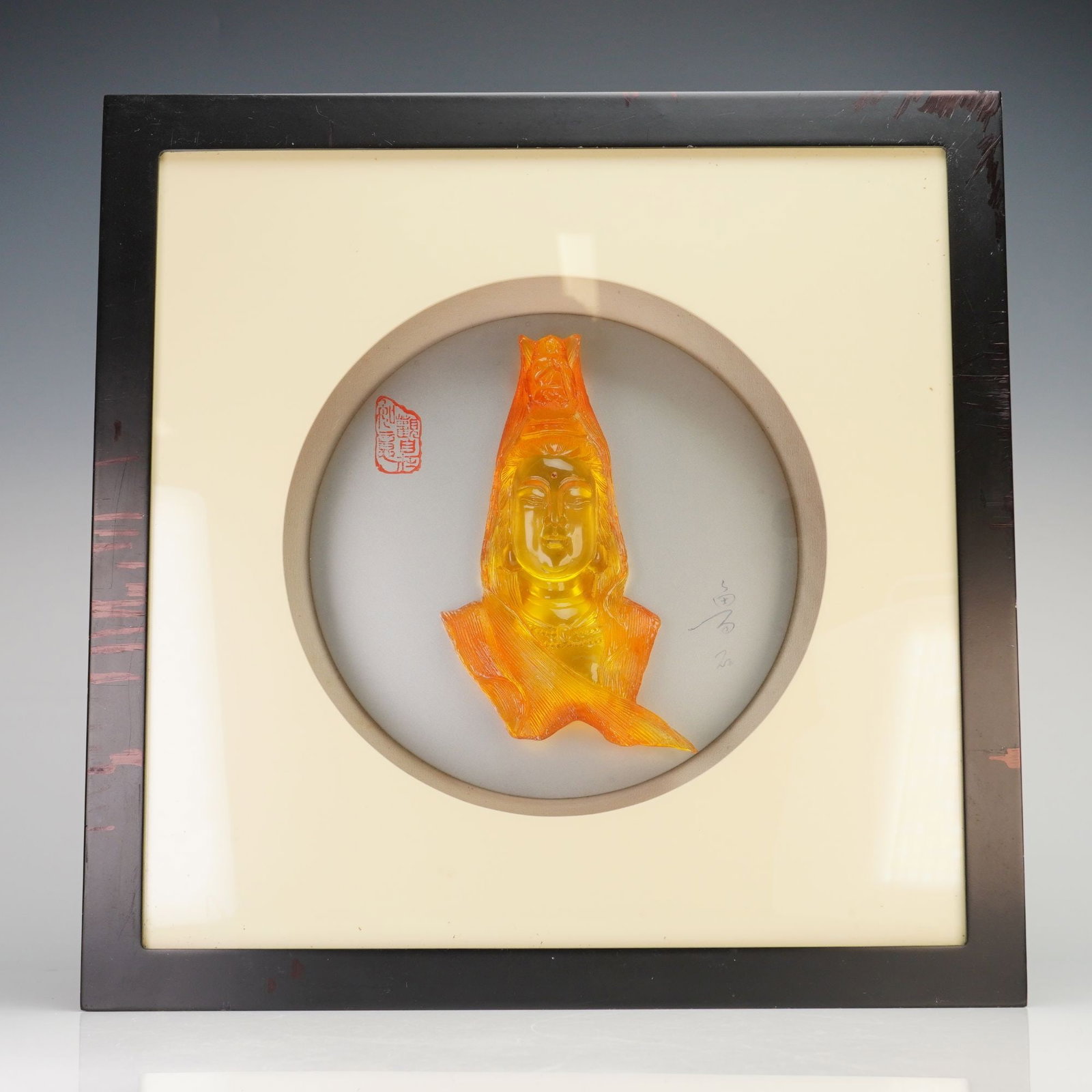 Contemporary Chinese Yellow Amber Resin Sculpture of Guan Yin: A contemporary framed yellow amber resin sculpture of Guan Yin, the Goddess of Mercy. The low-relief bust is rendered in a translucent honey-amber hue, depicting the deity with a serene facial express