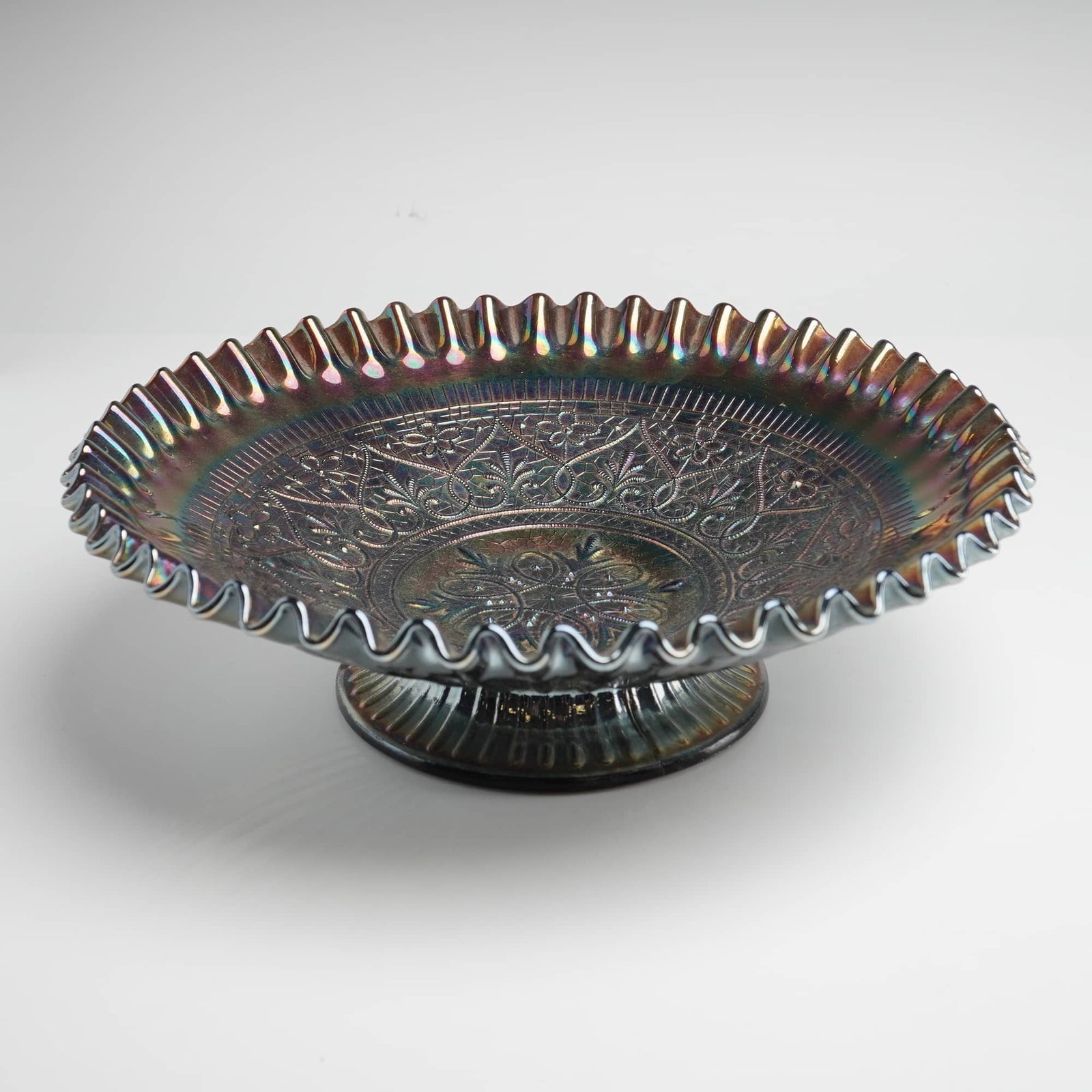 Fenton Hearts & Flowers Amethyst Carnival Glass Ruffled Pedestal Bowl: This elegant carnival glass bowl was produced by the Fenton Art Glass Company in the "Hearts & Flowers" pattern. The intricate interior design features a central floral medallion encircled by a delica