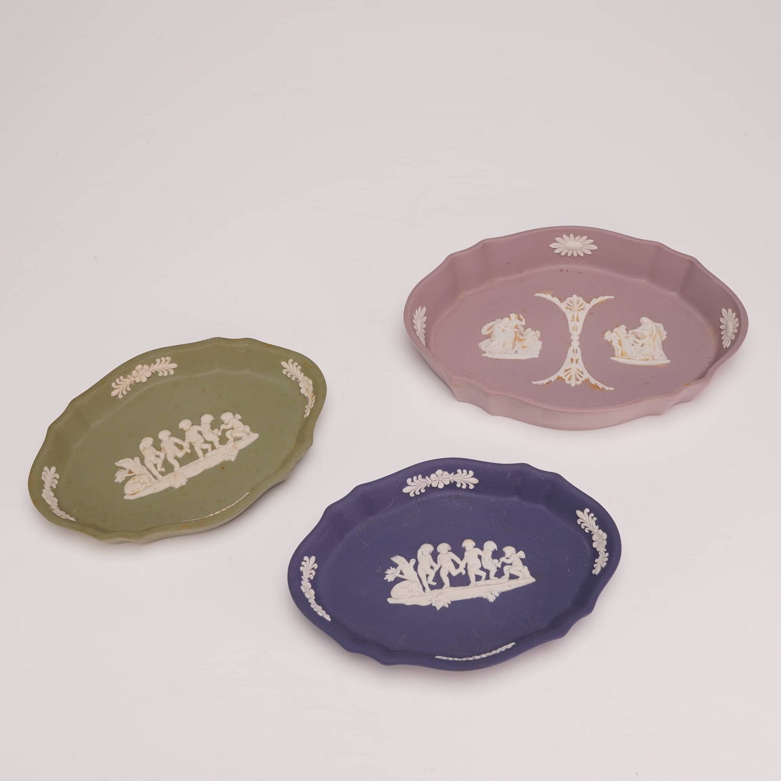 3pc Wedgwood Jasperware Small Oval Trinket Dishes: This trio of small oval pin dishes is composed of Wedgwood jasperware, a type of unglazed stoneware characterized by a matte finish and applied white bas-relief decoration known as sprigging. The set