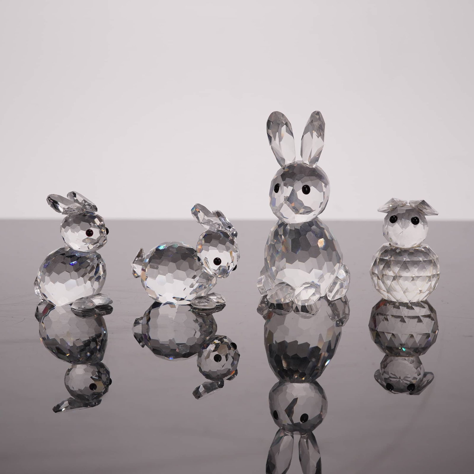 Swarovski Silver Crystal Rabbit Figurines: This collection of four faceted lead crystal figurines is from the Swarovski Silver Crystal line, featuring various rabbits from the Woodland Friends and Barnyard Friends series. The group includes a