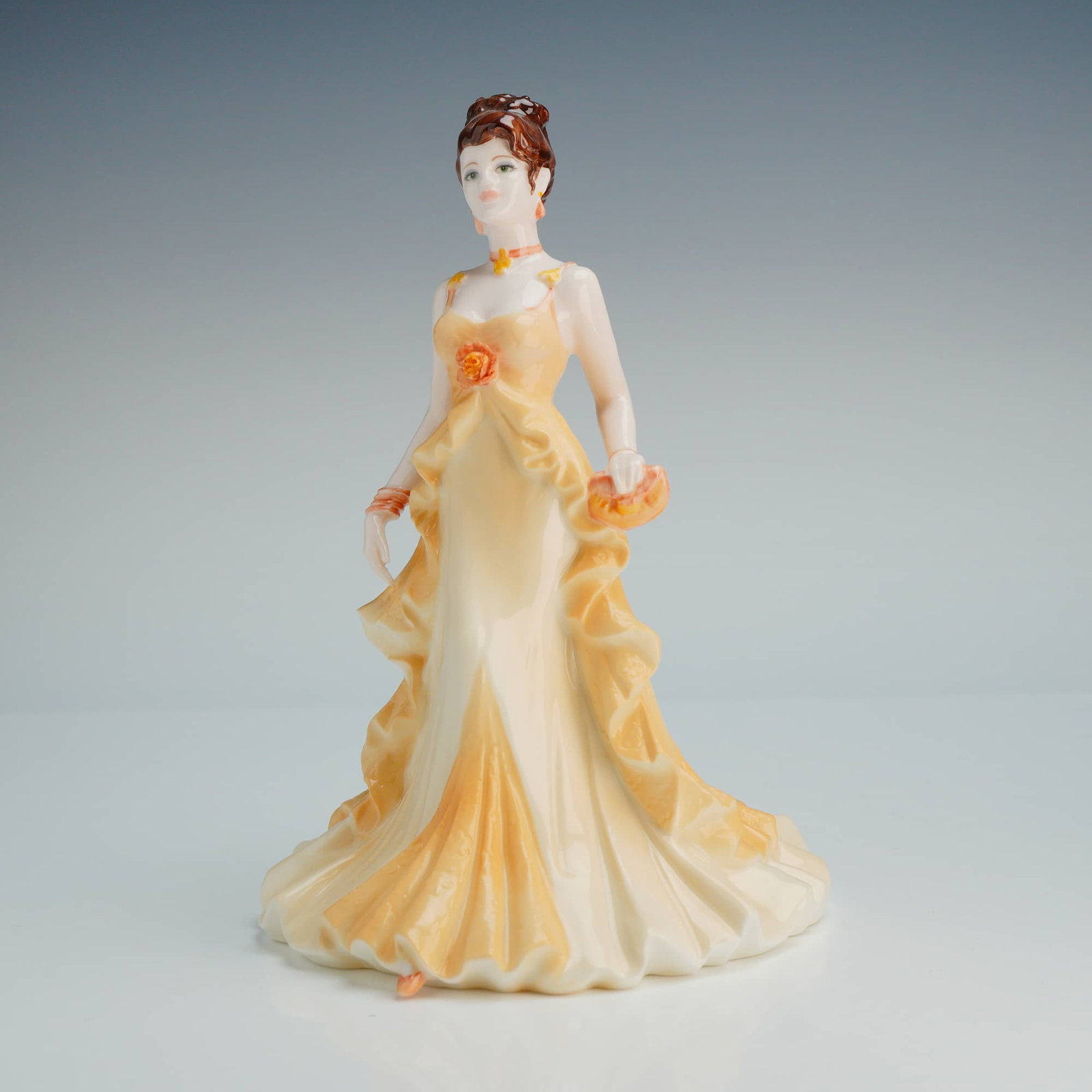 Coalport Collingwood Collection Figurine, Beverley: This hand decorated figure depicts a standing female in a floor-length yellow and cream ruffled gown featuring a floral corsage at the bodice. The figure has brown hair styled in an updo with orange f