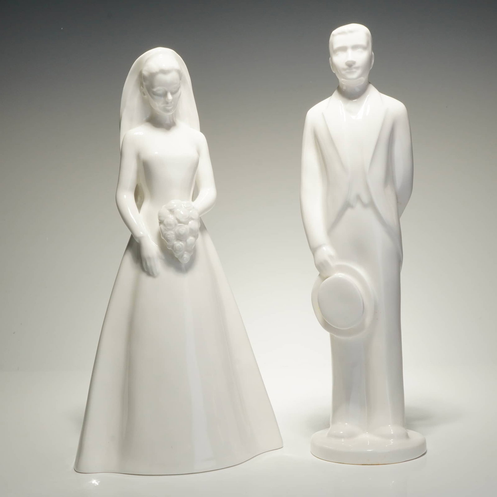 2pc Coalport Moments Bone China Figurines, The Bride and The Groom: A duo of white glazed bone china figurines from the Moments by Coalport collection, titled The Bride and The Groom. These contemporary-style figures are rendered with a high-gloss monochromatic finish