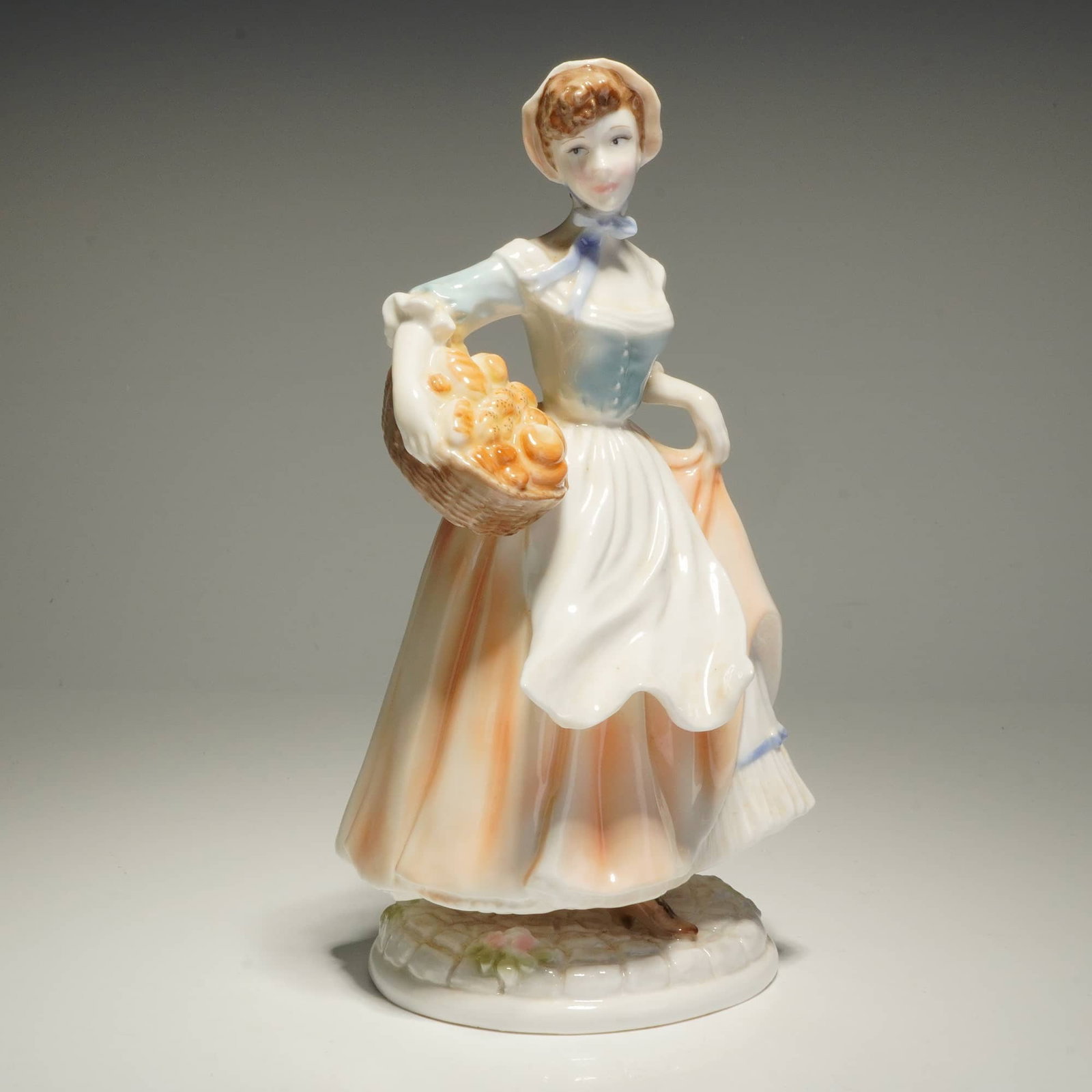 Royal Worcester Pastoral Collection Baker's Wife Limited Edition Figurine: A Royal Worcester fine porcelain figurine titled Baker's Wife from the Pastoral Collection. The figure is modeled in 18th-century style attire, featuring a pale blue bodice, white apron, and a peach-t