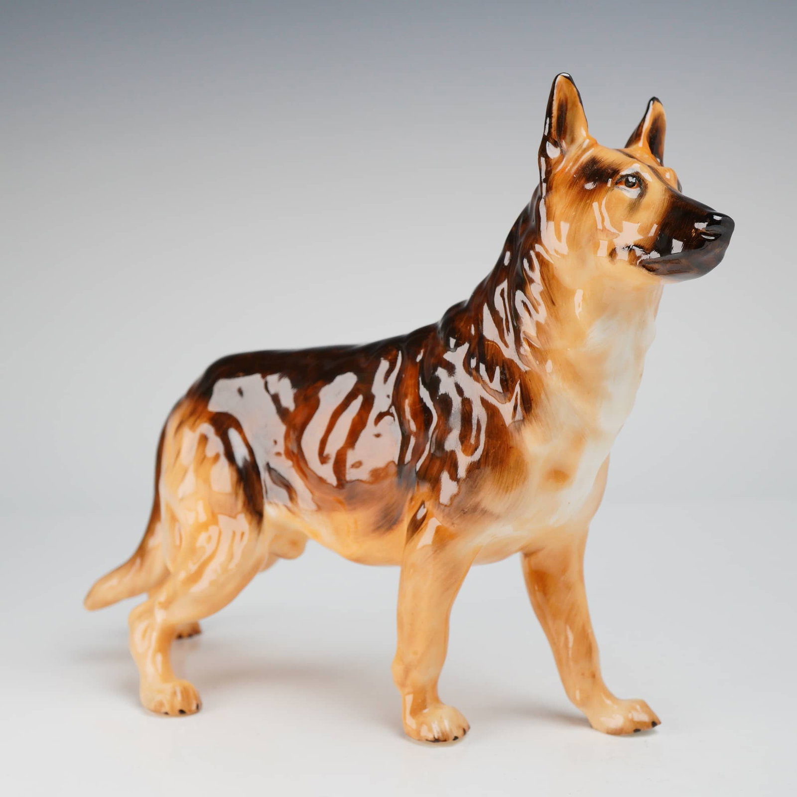 Royal Doulton Bone China German Shepherd Dog Figurine HN1116: A glossy brown, black, and tan bone china German Shepherd dog figurine, marked Royal Doulton HN1116, accompanied by its original green box. Dimensions: 8.00"L x 3.00"W x 6.25"H Weight: 8.00oz