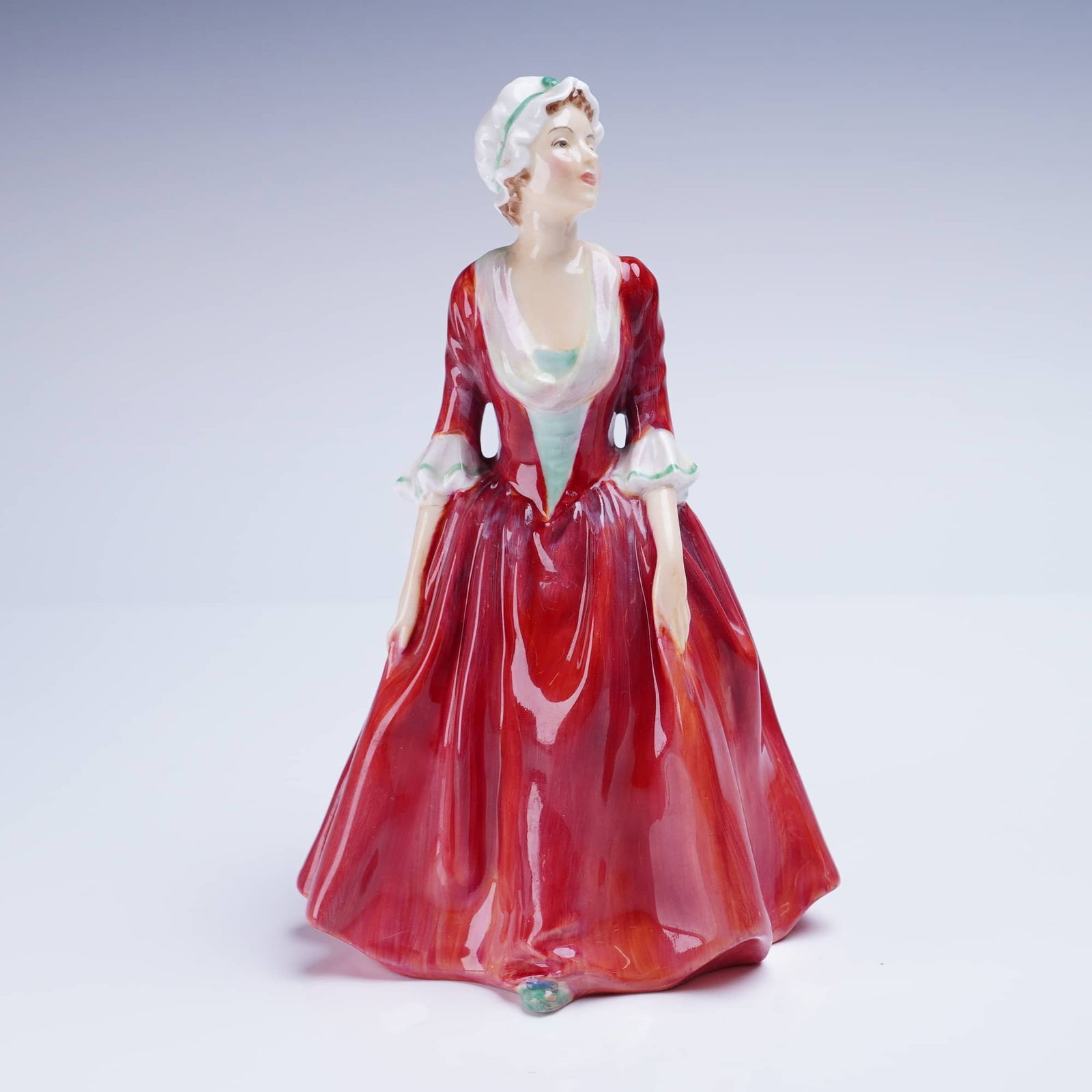 Royal Doulton Figurine Gwyneth HN1980: A glazed bone china figurine manufactured by Royal Doulton, titled Gwyneth. The standing female figure is depicted in a voluminous, period-appropriate gown rendered predominantly in glossy crimson red