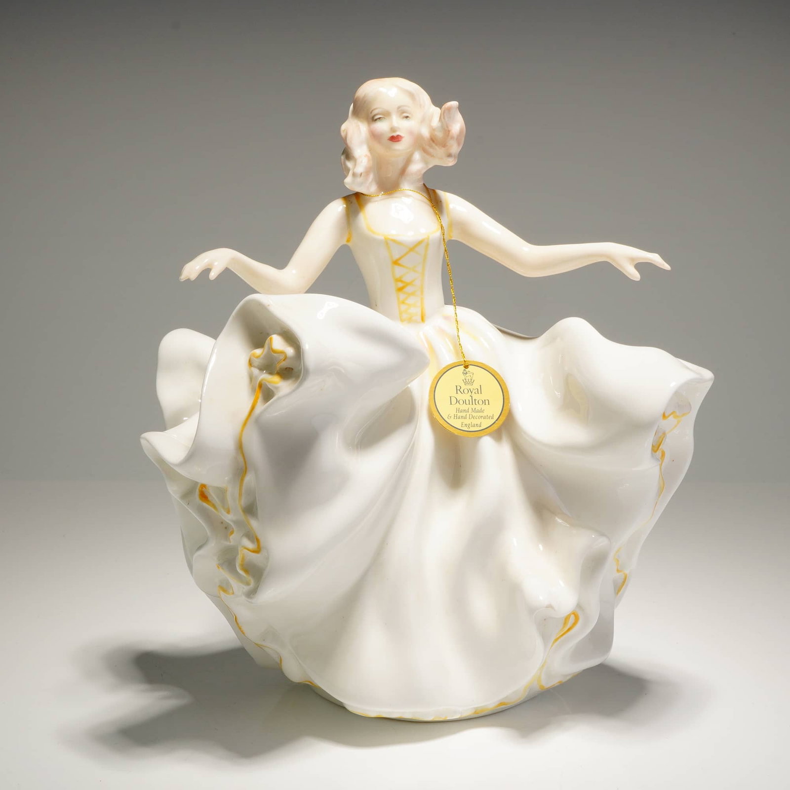 Royal Doulton Figurine Sweet Seventeen HN 2734: A bone chine figurine manufactured by Royal Doulton, titled Sweet Seventeen, model number HN2734. The figurine depicts a woman in a flowing white dress with yellow accents. The underside features the