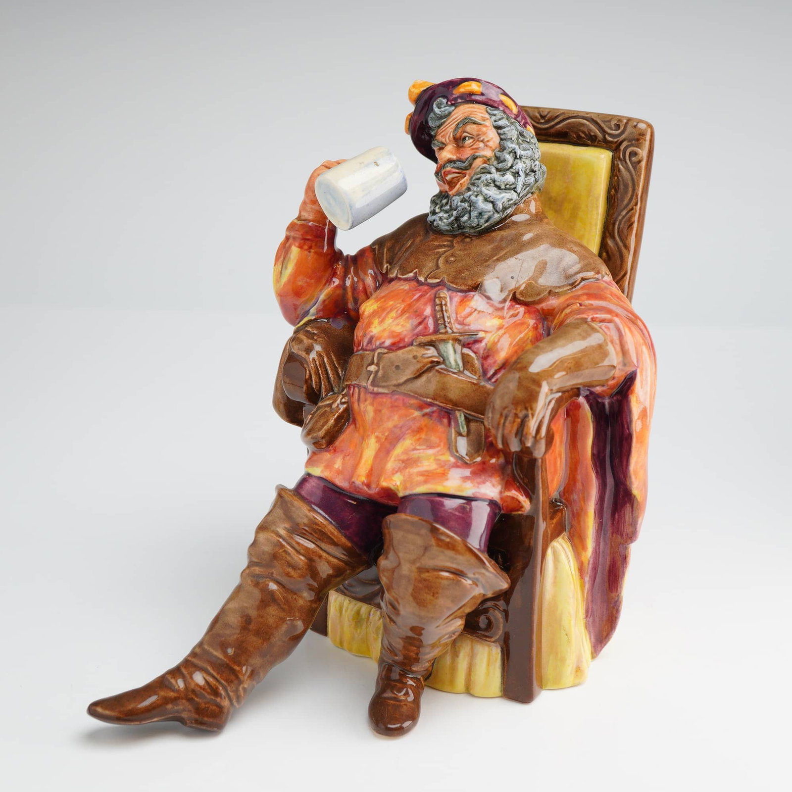 Royal Doulton Figurine The Foaming Quart HN2162: A Royal Doulton Figurine, The Foaming Quart HN2162, depicting a seated man drinking, marked COPR. 1954, and finished in brown, orange, and yellow tones. Dimensions: 5.75"L x 4.50"W x 6.00"H