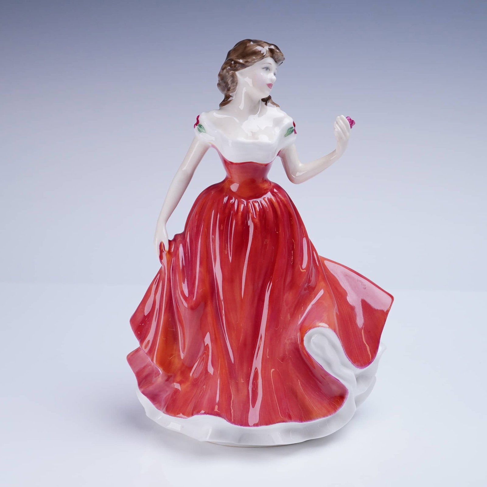 Royal Doulton Figurine, Marianne HN4153: A glazed porcelain figurine by Royal Doulton, titled "Marianne." The figure depicts a standing young woman modeled in a Romantic style, wearing a flowing, voluminous crimson red dress contrasting with