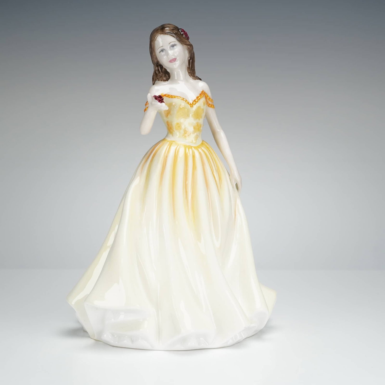 Royal Doulton Figurine, Rose HN4581: A bone china figurine by Royal Doulton, titled Rose, model number HN 4581. The piece depicts a standing lady in a flowing, glazed yellow and white ballgown. The base features markings including the Ro