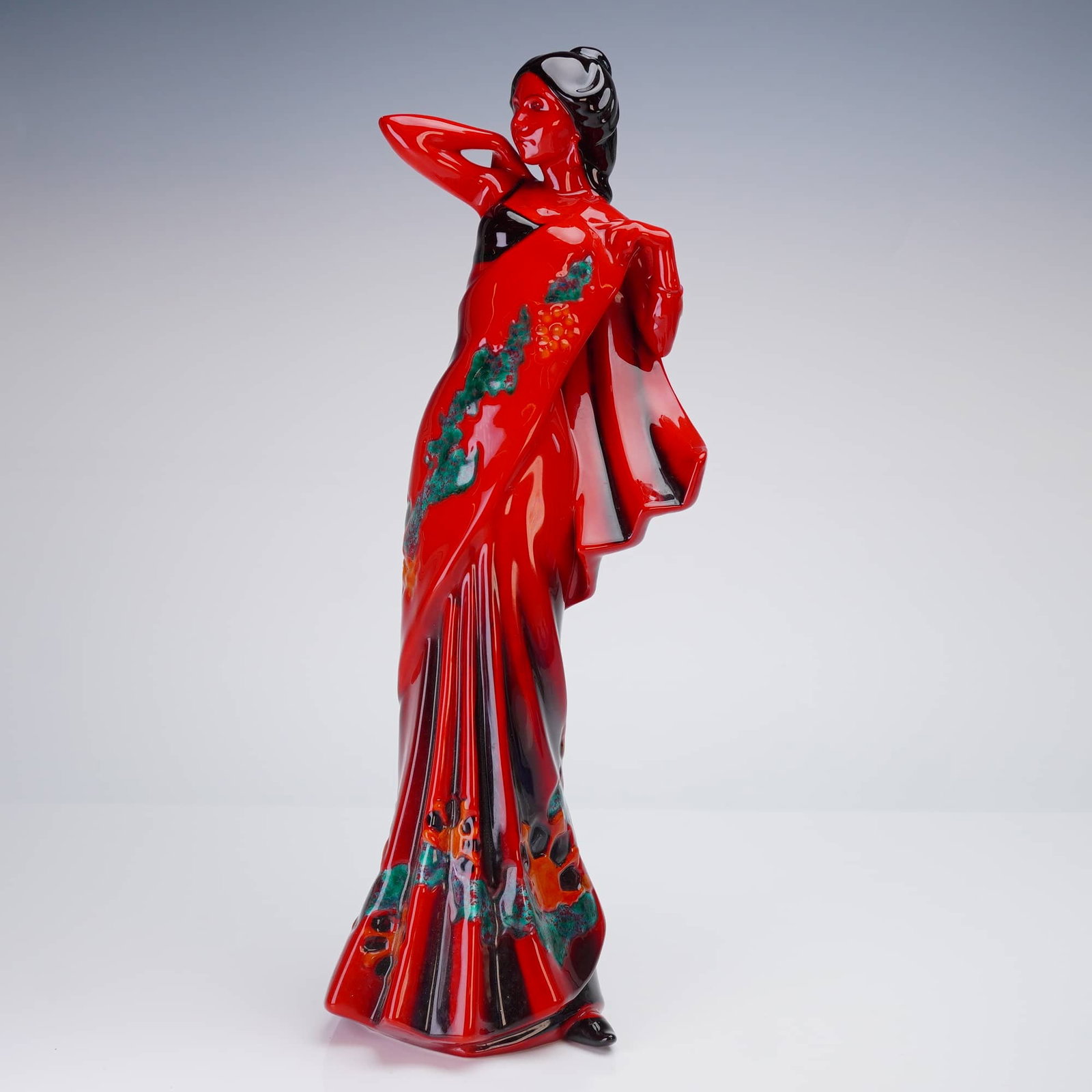 Royal Doulton Flambe Figurine Eastern Grace HN 3858: A single ceramic figurine by Royal Doulton, executed in the distinctive Flambé glaze technique. The piece, titled "Eastern Grace," depicts a stylized standing woman or dancer in a dramatic pose, drap