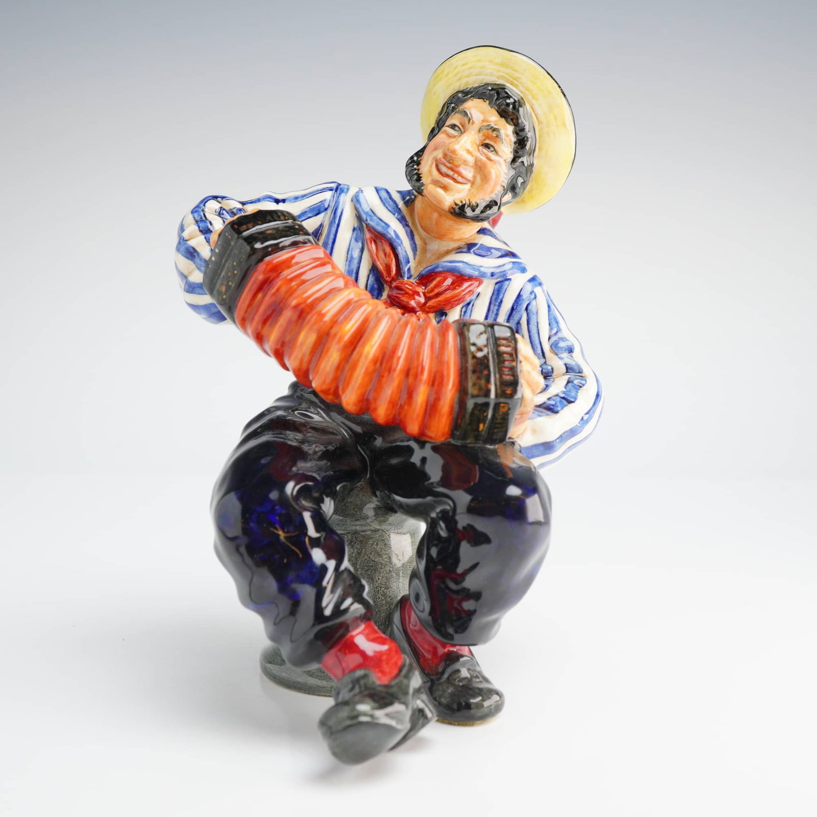 Royal Doulton Jolly Sailor HN 2172 Figurine: A Royal Doulton Figurine, Jolly Sailor HN2172, depicting a multi-colored ceramic seated sailor in a striped shirt playing an accordion, marked DOULTON COPR. & 1955. Dimensions: 4.50"L x 4.50"W x 6.50"