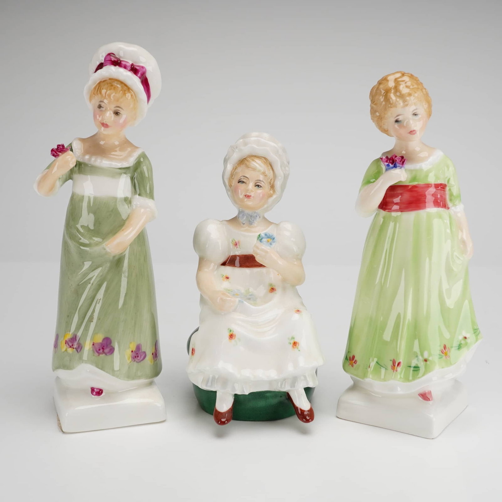 Three Royal Doulton Bone China Figurines Ruth HN2799 Tess HN2865 and Kathy HN2346: Three Royal Doulton bone china figurines from the Kate Greenaway Collection, including the models Ruth HN 2799, Kathy HN 2346, and Tess HN 2865. These English bone china figures are depicted in Regenc