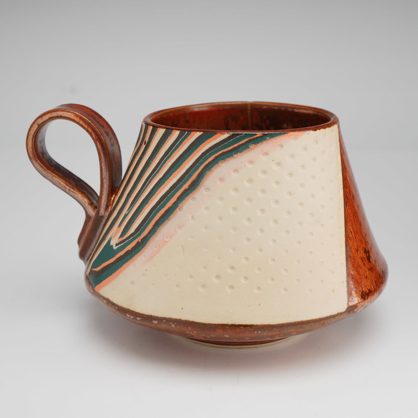 Knutzen Studio Pottery Cup with Multi-Glaze Decoration: A contemporary studio ceramic mug by Knutzen, featuring a distinctive tapered conical body and a hand-applied loop handle. The exterior is expertly decorated with three vertical registers showcasing v