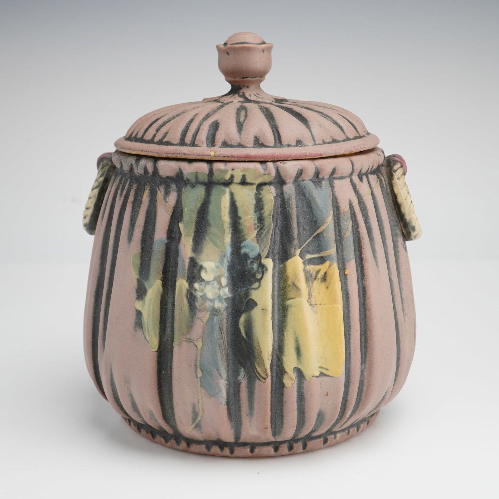 Weller Louella Pottery Jar with Lid: This Weller Pottery lidded jar is a notable example of the Louella line, produced circa 1915. The earthenware vessel features a globular, fluted body with a matching domed lid topped by a rosebud-shap