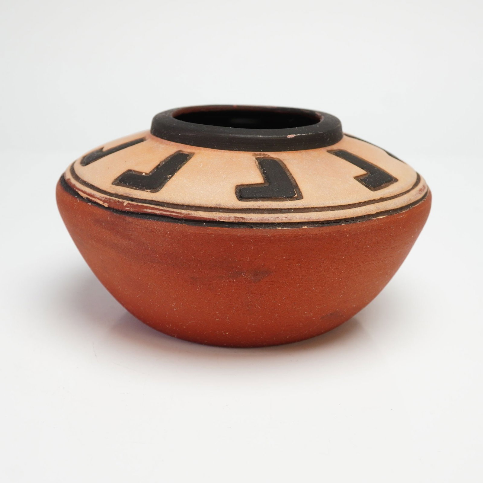 Weller Souevo Pottery Seed Jar with Geometric Motifs: The vessel is traditionally hand-coiled and decorated with a vibrant red-slipped base and a buff-colored slip on the shoulder. The shoulder is painted with a series of repeating black geometric hook-s