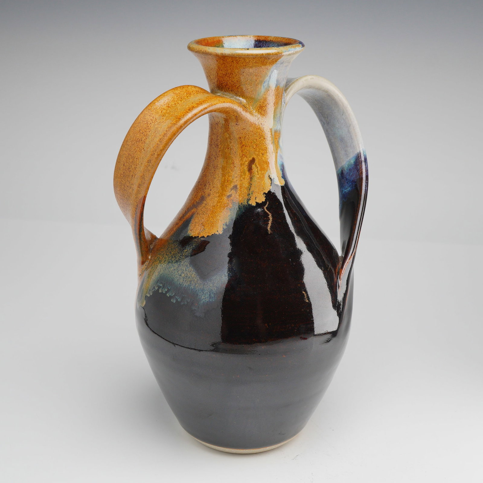 Mack Chrisco Seagrove Studio Pottery Two-Handled Drip Glaze Stoneware Vase: This contemporary studio pottery vase is the work of Mack Chrisco, a prominent artist within the Seagrove, North Carolina, potting tradition. The piece features a bulbous stoneware body that tapers to