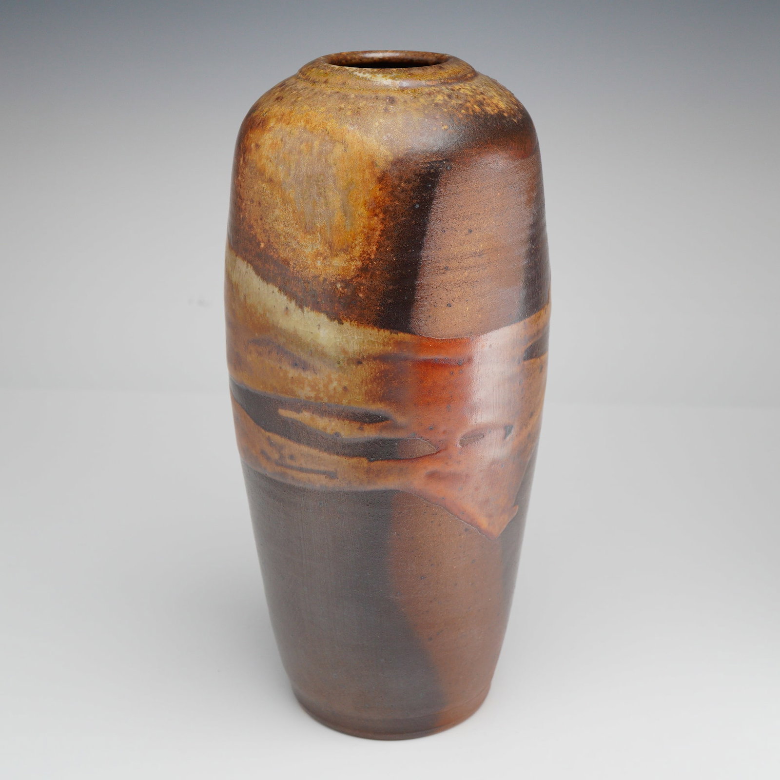 Dan Triece Dirtwood Pottery Stoneware Vase: This contemporary Dan Triece Dirtwood Pottery Raku stoneware vase dates from the late 20th to early 21st century. Originating from North Carolina, the vessel features a tall tapered ovoid form with a