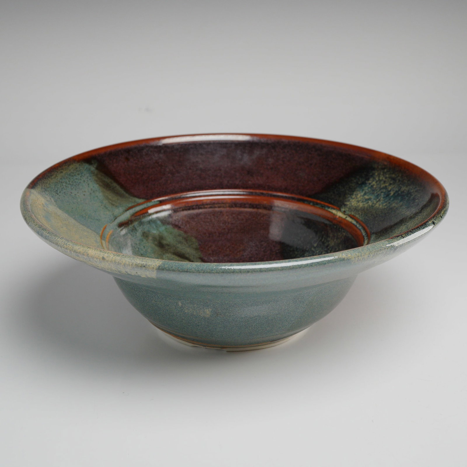 Terry Parker Studio Stoneware Bowl: Hand-thrown studio stoneware bowl by North Carolina potter Terry Parker of Loma Prieta Pottery. The form features a wide, gently flared rim and rounded body, finished in a striking transitional drip g