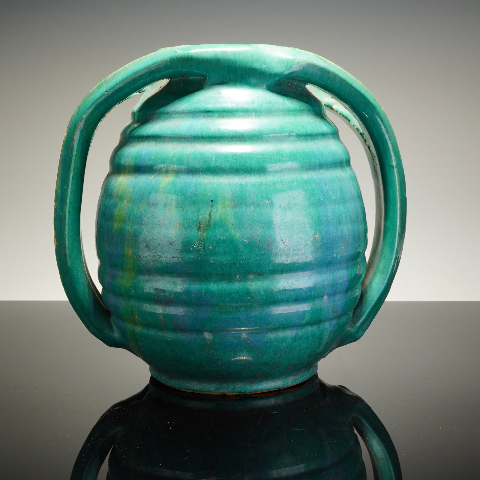 Rainbow Pottery North Carolina Double Handled Vase: This ceramic vessel features a bulbous, horizontally ribbed beehive body and two oversized loop handles extending from the lower body to the rim. The piece is finished in a turquoise glaze with yellow