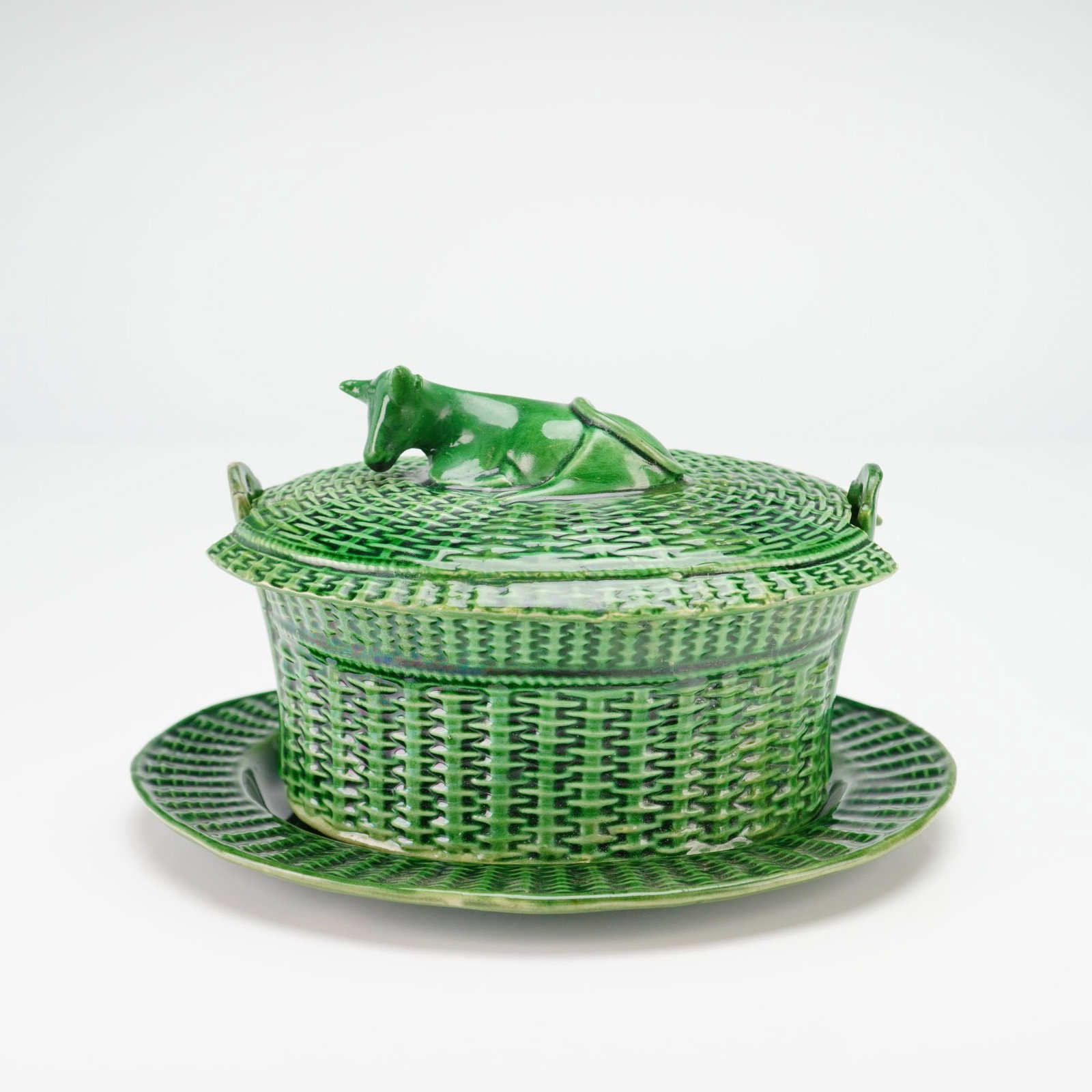 Green-Glazed Basketweave Lidded Bowl with Cow Finial and Plate: This ceramic lidded bowl, designed as a butter tub or small tureen, is executed in the style of late 18th or early 19th-century English green-glazed creamware, a tradition often associated with makers