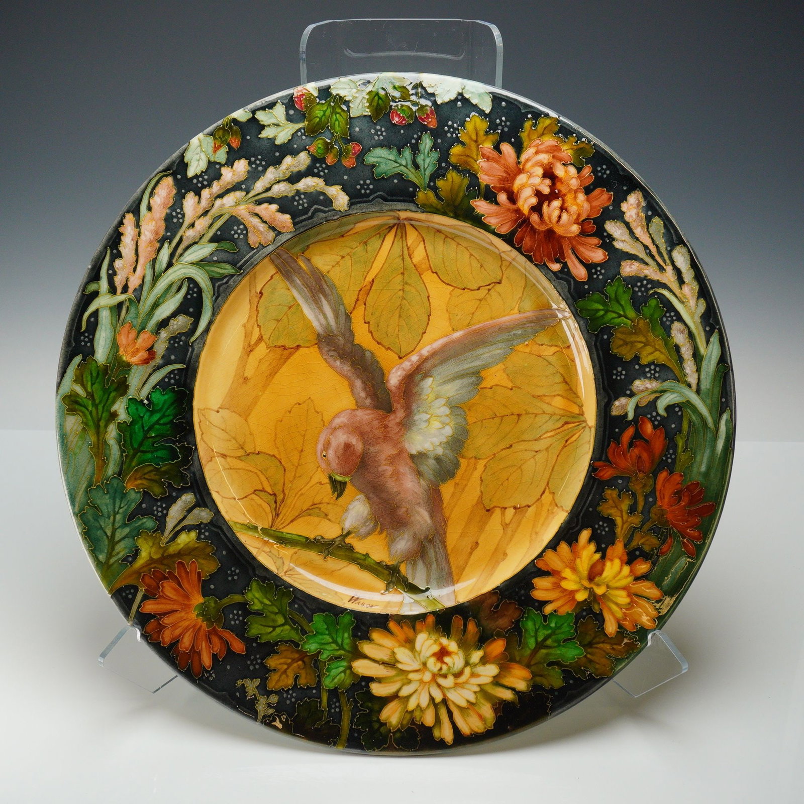 French Barbotine Earthenware Charger Signed Wallon: This French barbotine earthenware charger features a central medallion depicting a bird with outspread wings perched on a gnarled branch, set against a background of broad autumnal leaves. The wide bo