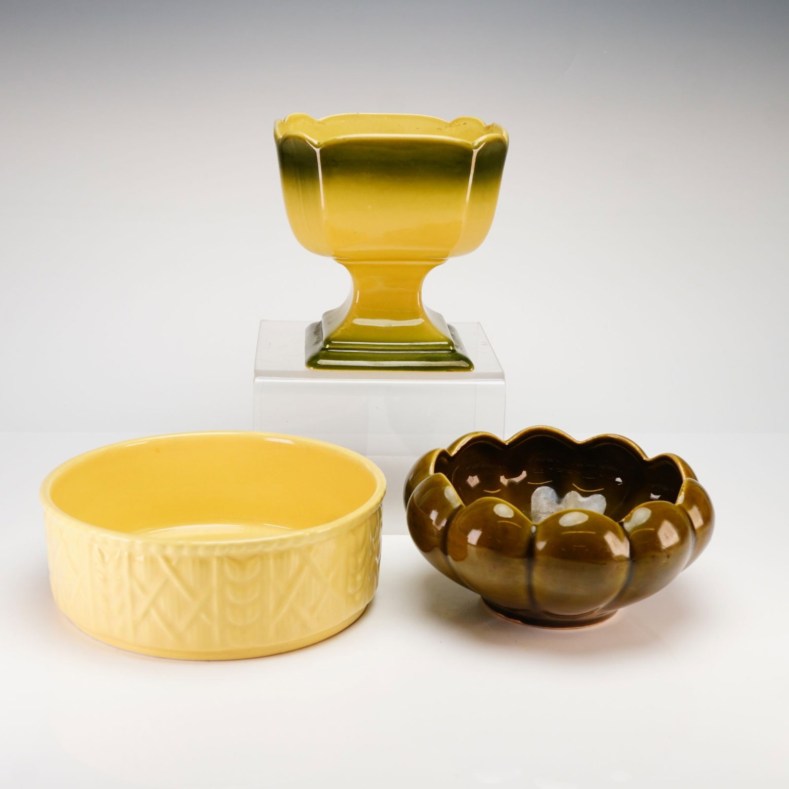 Three Floraline and Unmarked Yellow Pottery Planters: A trio of mid-century modern style glazed ceramic planters and bowls in shades of yellow and green. The collection features a small lobed olive green bowl marked on the underside 509 FLORALINE USA, a