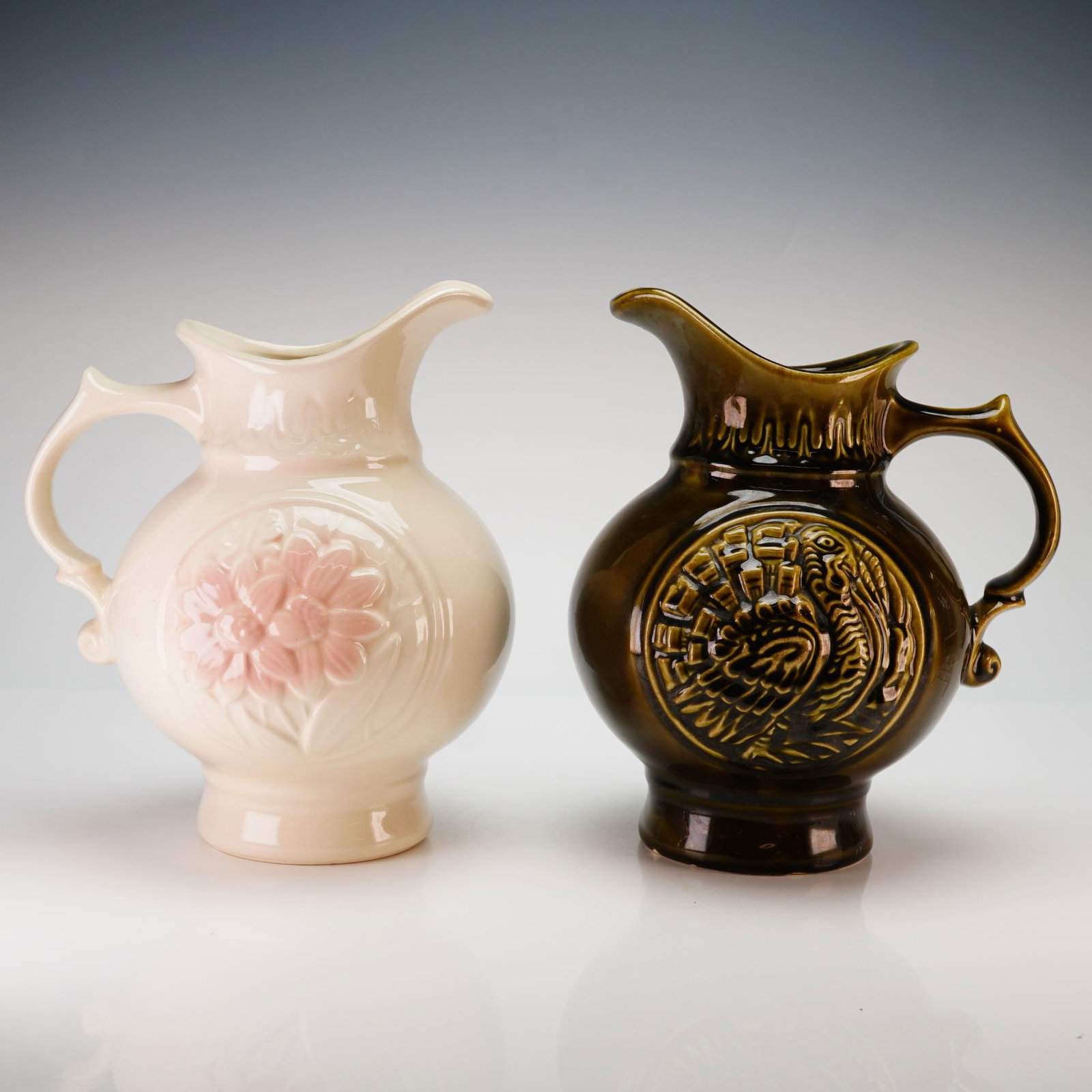Two McCoy MCP Glazed Pottery Pitchers: This lot features 2pc McCoy and MCP pottery pitchers dating to 1968. Each glazed ceramic vessel is constructed with a globular body, a flared rim with an integrated spout, and a decorative scrolled ha