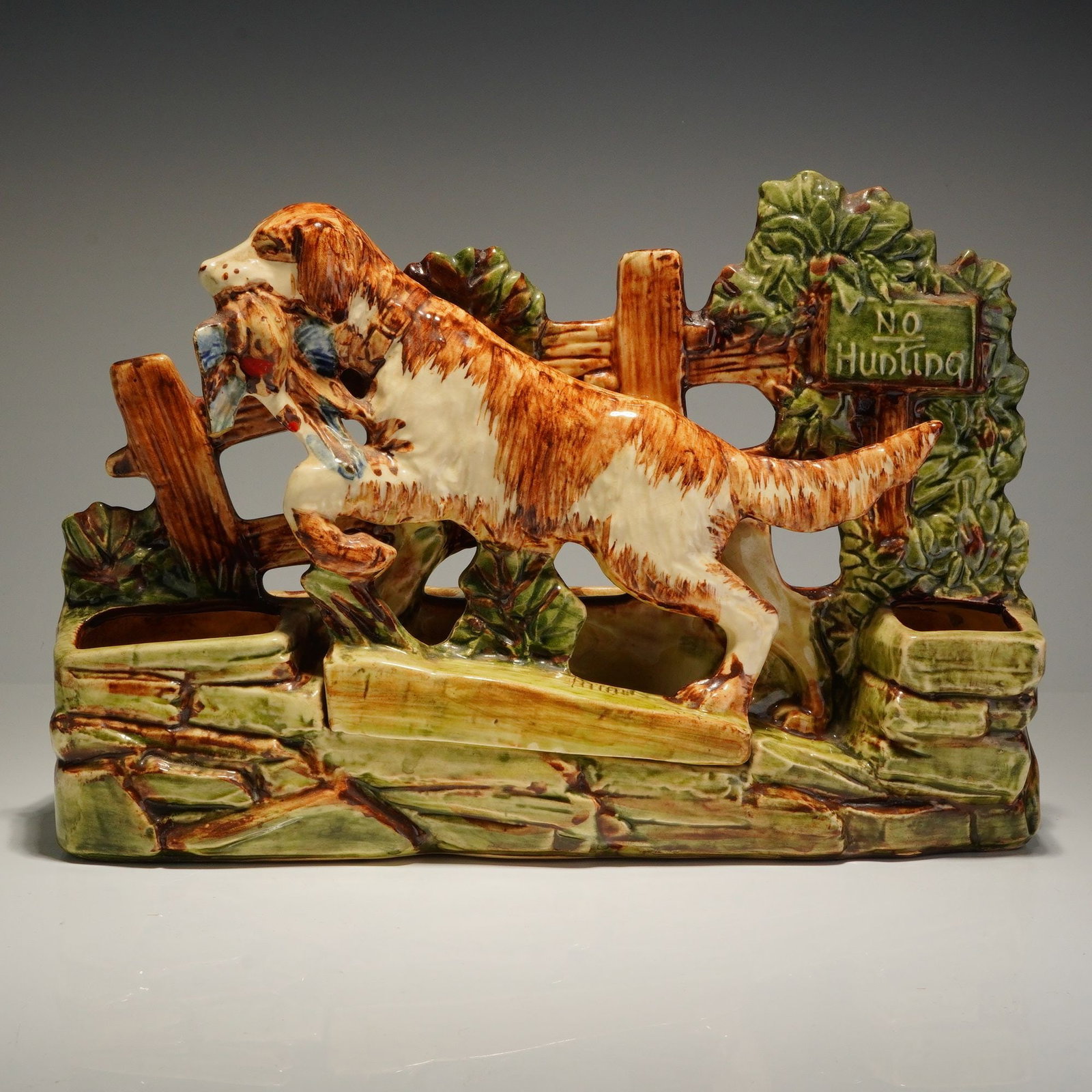 McCoy Pottery Bird Dog Hunting Spaniel No Hunting Planter: A McCoy Pottery ceramic planter, identified as the bird dog planter model from circa 1954. This natural hand decorated piece features a relief-molded sporting scene depicting a liver and white hunting